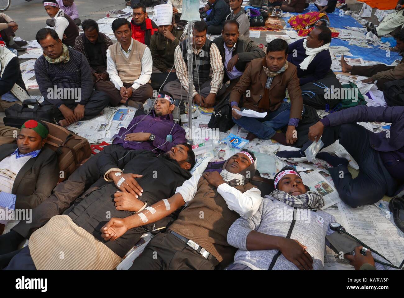 Dhaka, Bangladesh. 5th Jan, 2018. Non-MPO (monthly pay order) teachers from different non-government institutions, lay down as in the street as they continue the five day of their fast unto death hunger strike program in front of the National Press Club in Dhaka, Bangladesh. Some hundred teachers went for hunger strike demanding their inclusion of the government-approved educational MPO facilities while more than 80,000 teachers from 5,242 non-MPO institutions are working without any pay, according to the leaders. © Monirul Alam Credit: Monirul Alam/ZUMA Wire/Alamy Live News Stock Photo