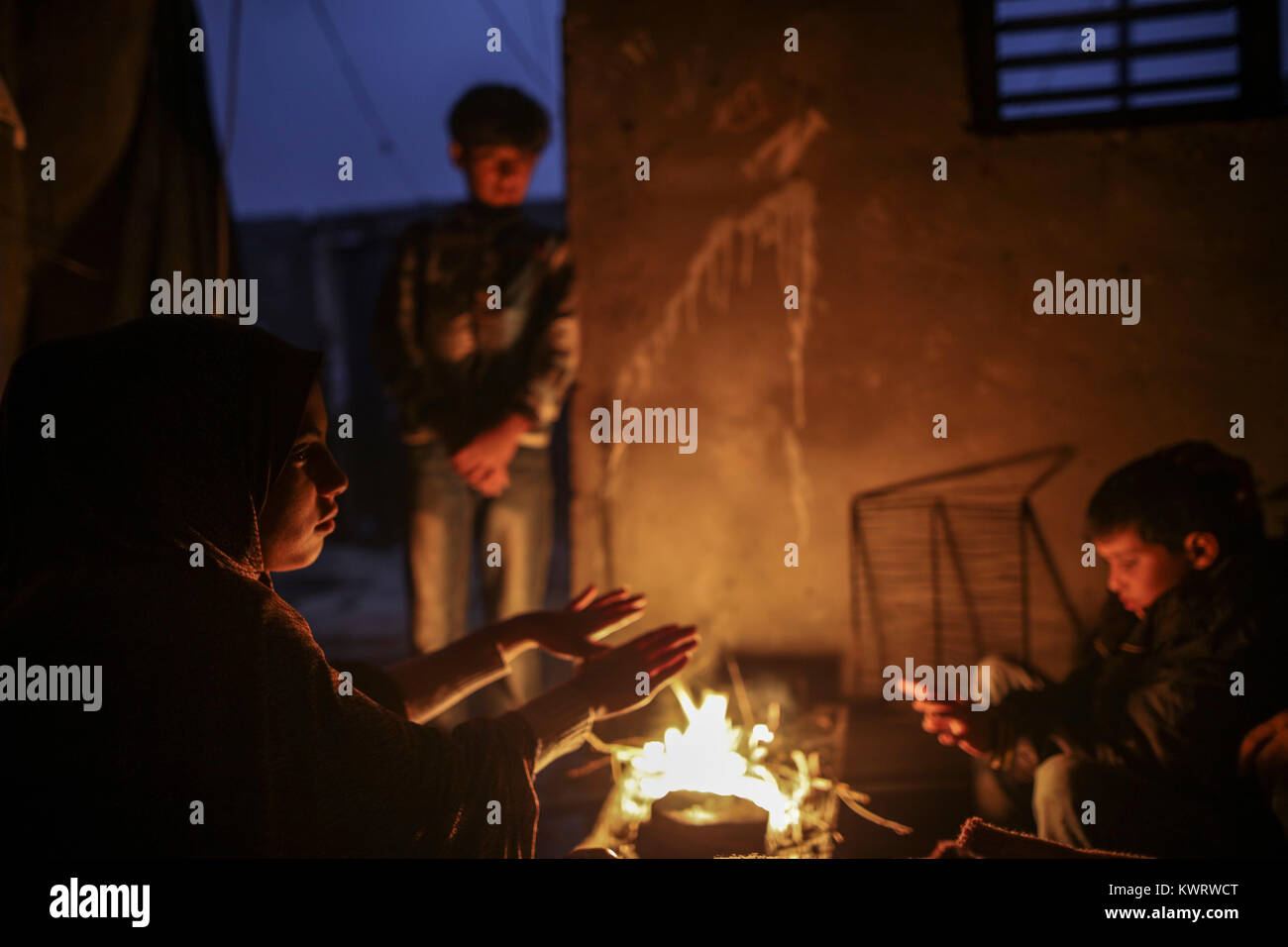 Members of a Palestinian family gather around fire to stay warm, amid a ...