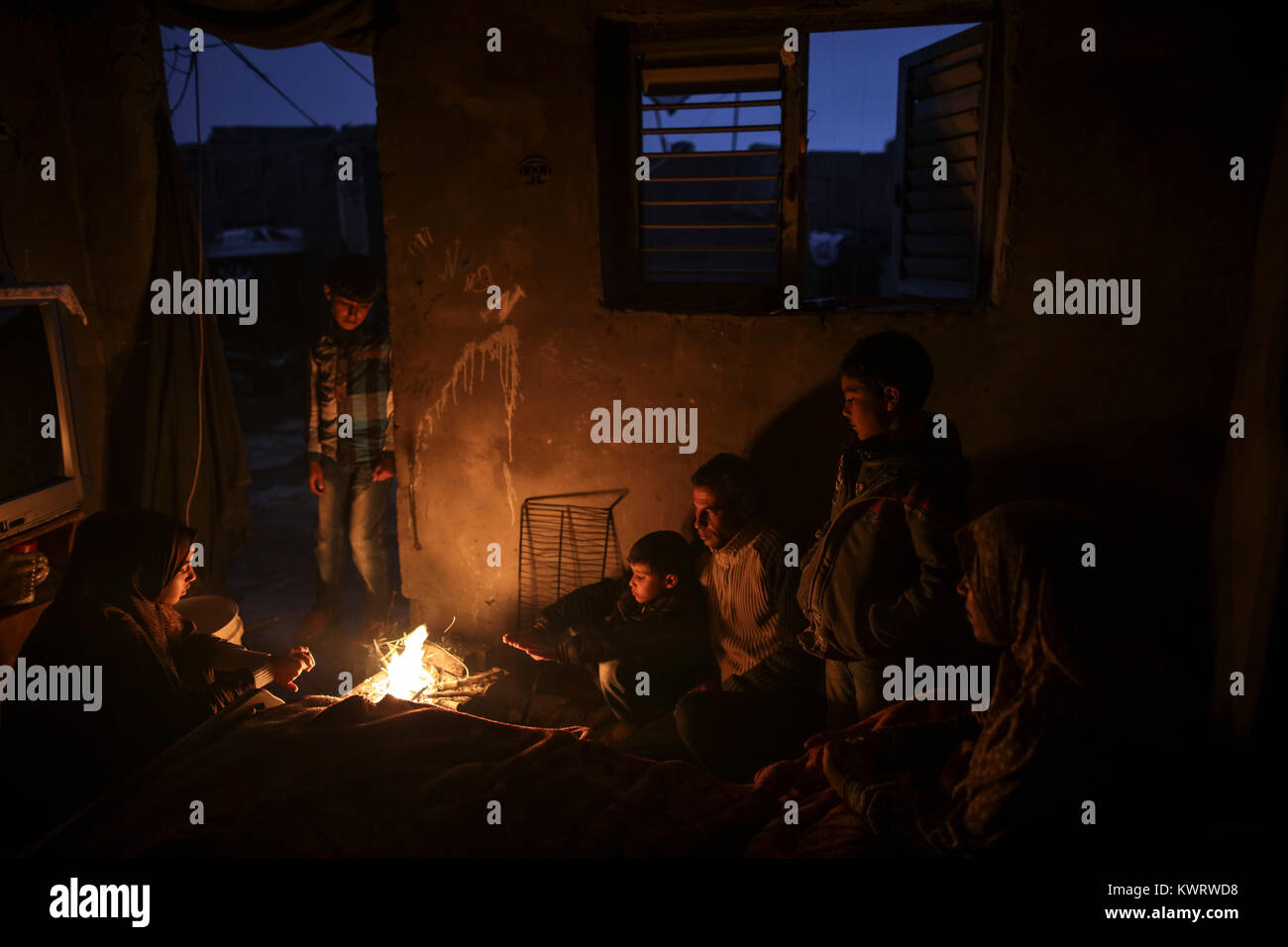 Members of a Palestinian family gather around fire to stay warm, amid a ...