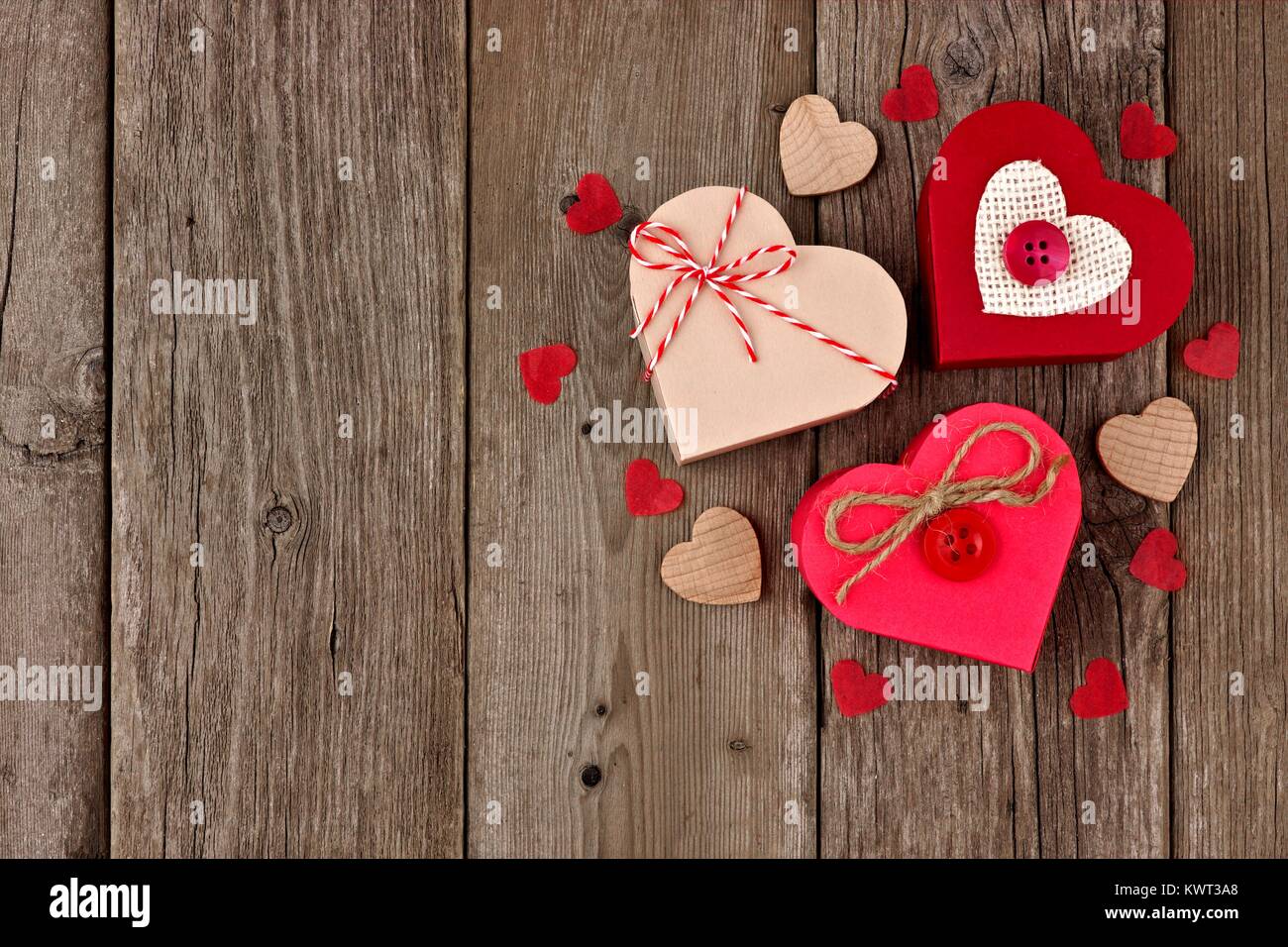 Valentines Day heart shaped gift boxes with red and burlap trim in a cluster over wood Stock Photo