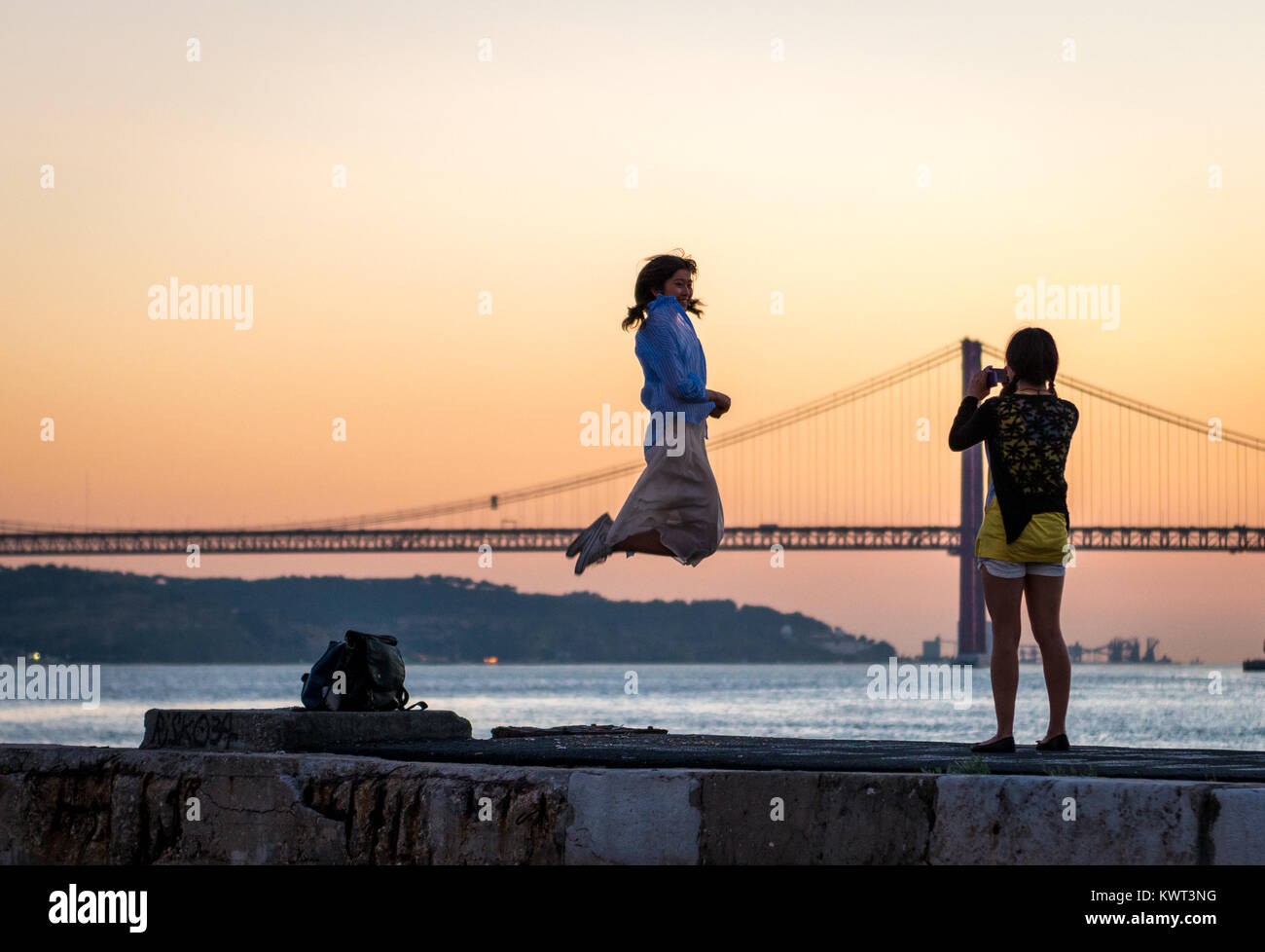 Girl taking a photo of a friend jumping for joy in Lisbon Stock Photo