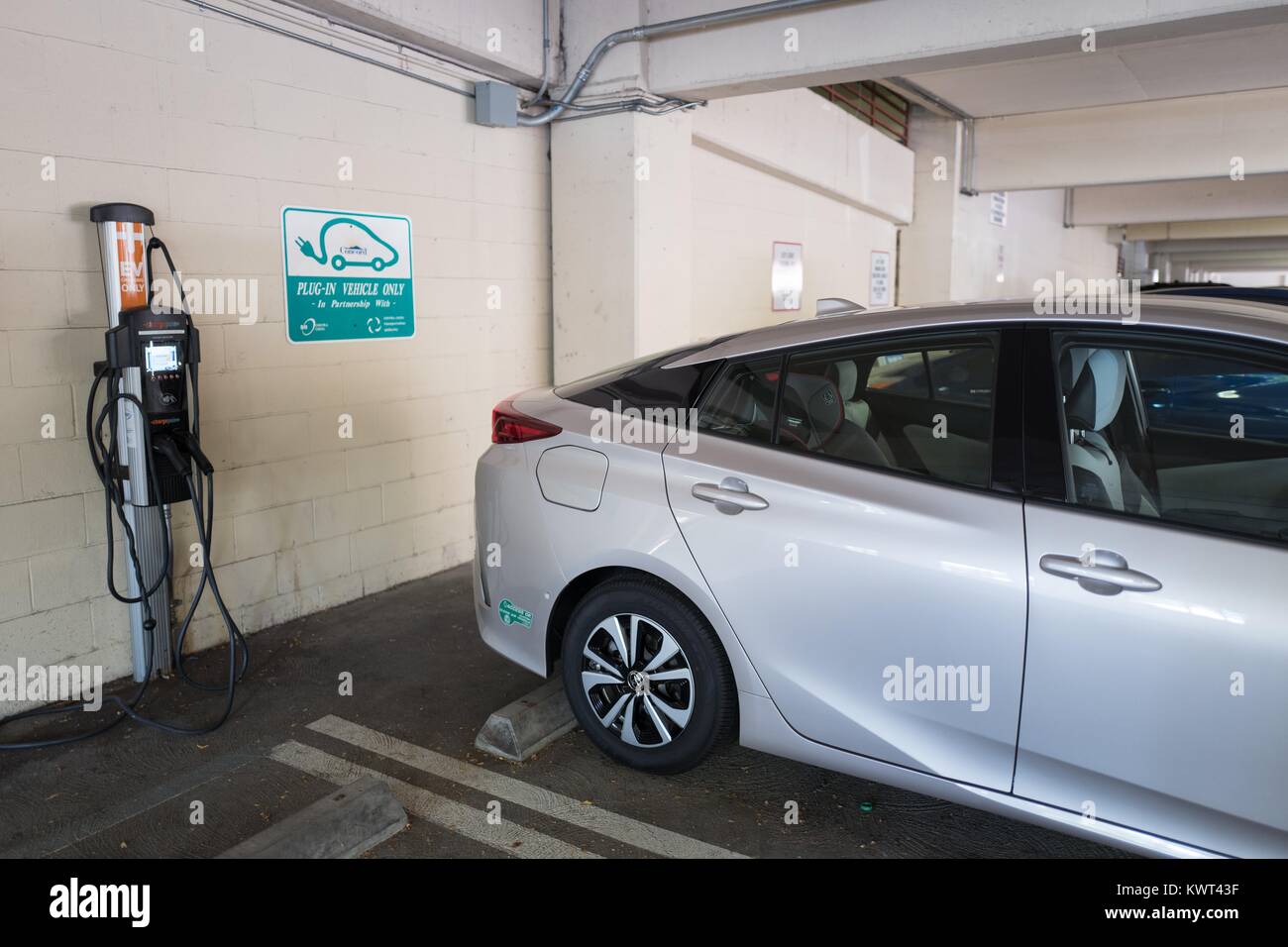 A city-owned plug in hybrid Toyota Prius automobile is plugged in and charging at an electrical vehicle charging station in a municipal garage in Concord, California, September 8, 2017. Stock Photo