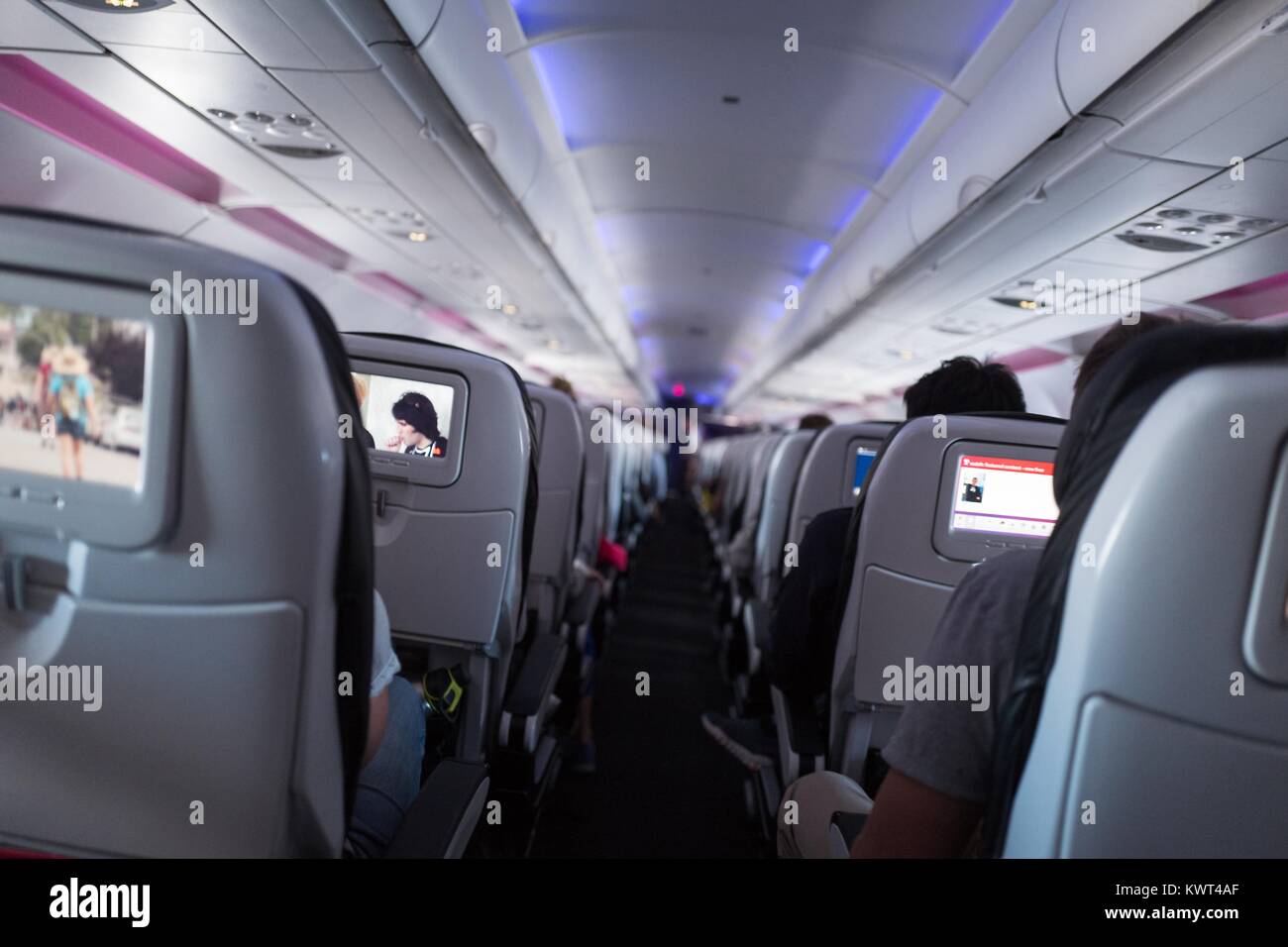 View down the aisle of the coach class section of a Virgin America aircraft in flight, with in-flight entertainment consoles on seat backs visible, September 13, 2017. Stock Photo