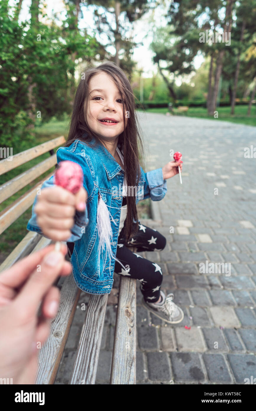 Girl sitting on bench with candies Stock Photo