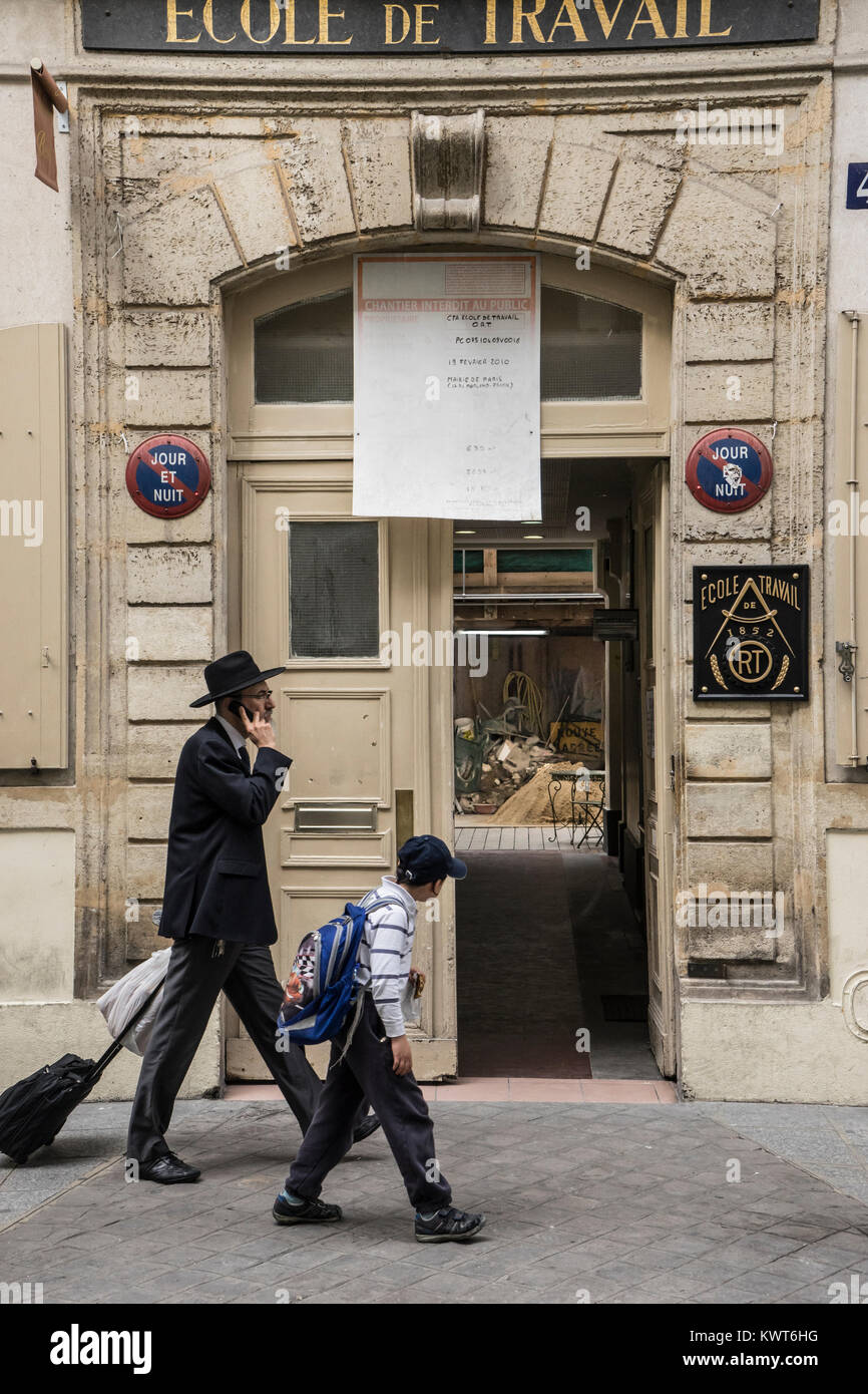 France, Paris, Jewish man and boy looking in while walking passed a trade school. Stock Photo
