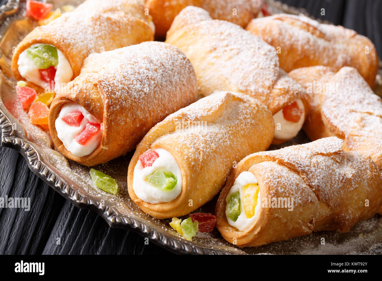 Italian pastries cannoli with cheese cream and candied fruit closeup on a plate. horizontal