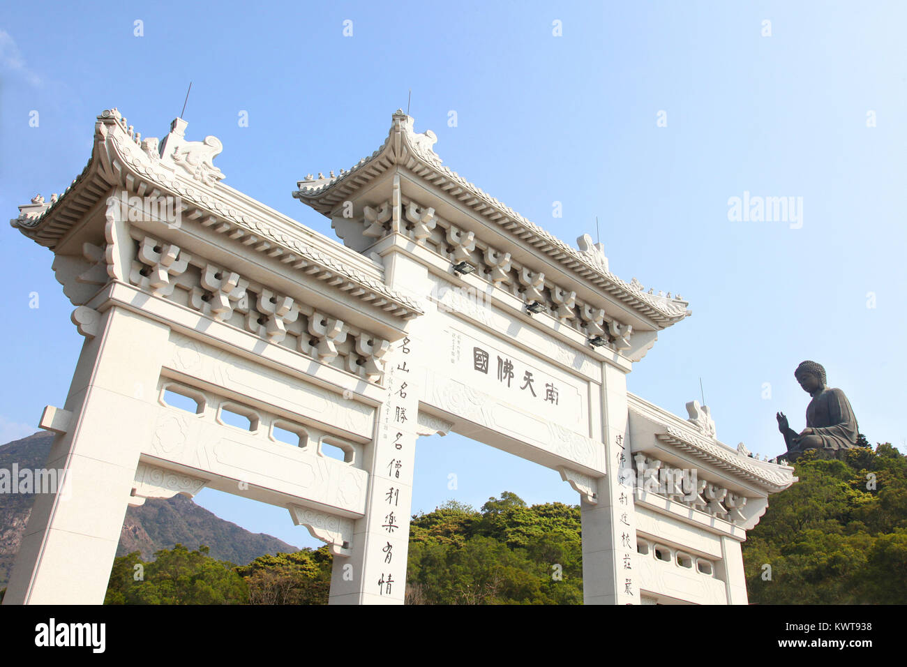 Entrance gate to Tian Tin monastery and the Big Buddha on the mountain behind at Ngong Ping village on Lantau Island, Hong Kong, China. Stock Photo