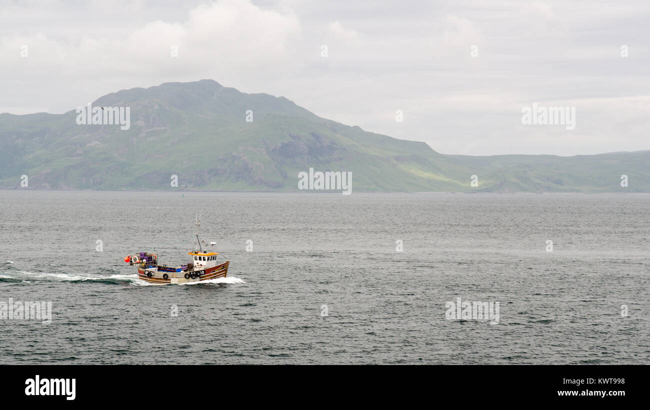 Tobermory, Scotland, UK - June 21, 2014: A fishing boat in the Sound of Mull passes mountains of the Ardnamurchan Peninsula in the West Highlands of S Stock Photo