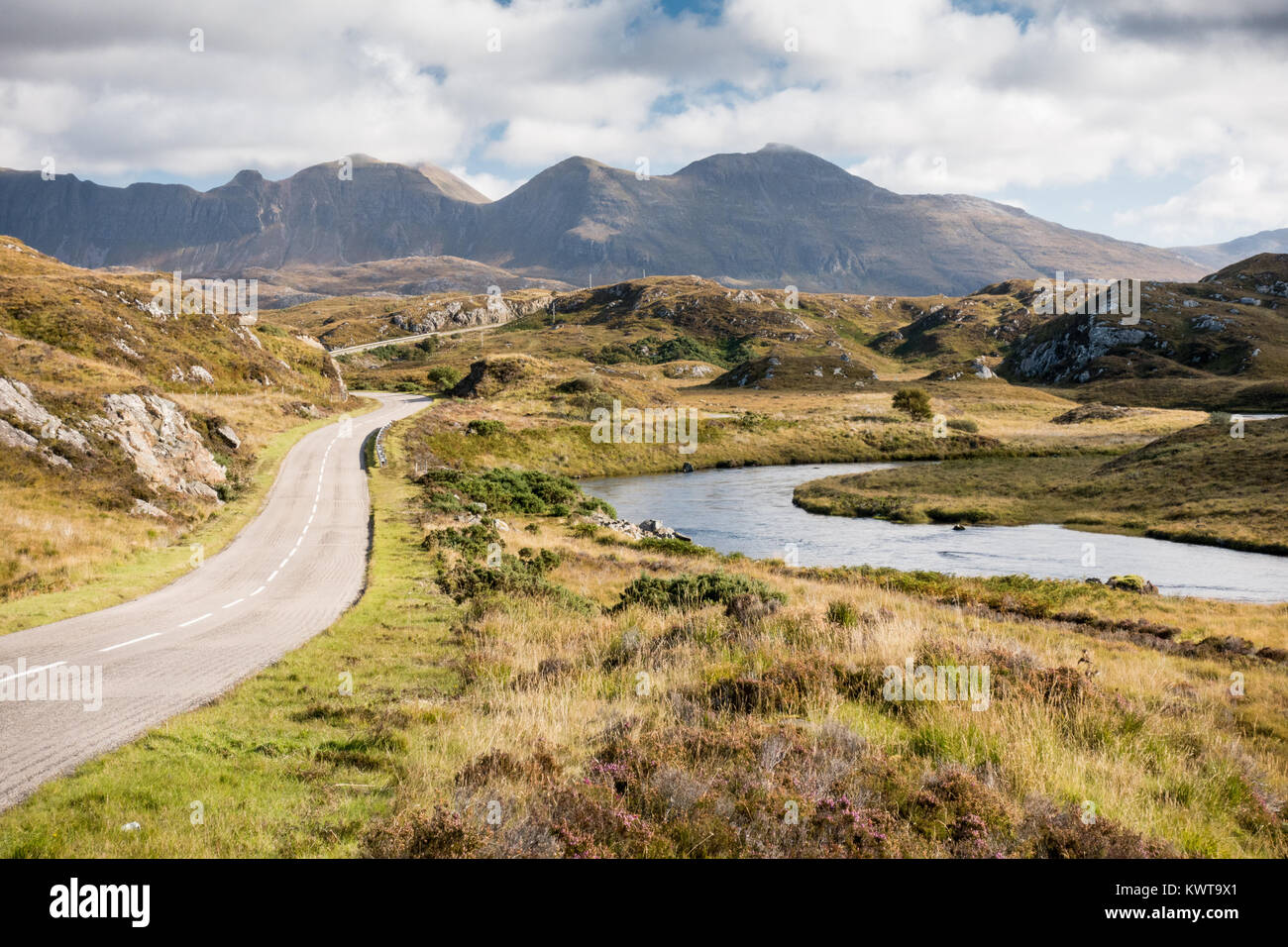 The A837 road, part of the North Coast 500 route, meanders past rivers and low hills in the glacial landscape of Assynt, with Quinag mountain in the d Stock Photo