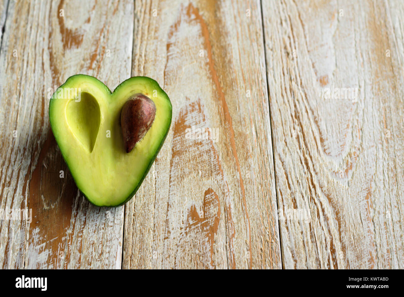 Heart shaped avocado half on wooden background. Retouched Stock Photo