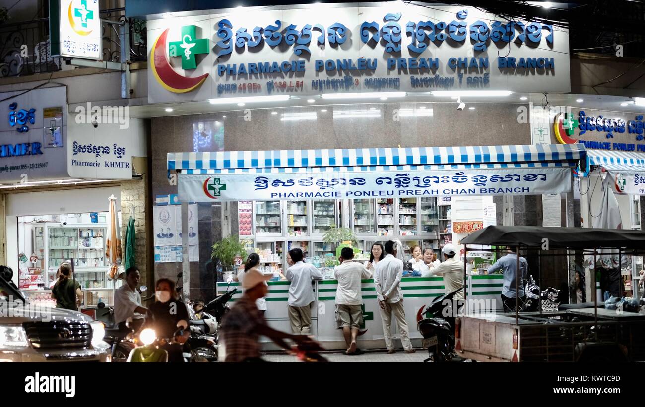 pharmacy drug store chemist pill sellers over-the-counter drugs Phnom Penh Cambodia costumers at counter at night prescription medicine business Stock Photo