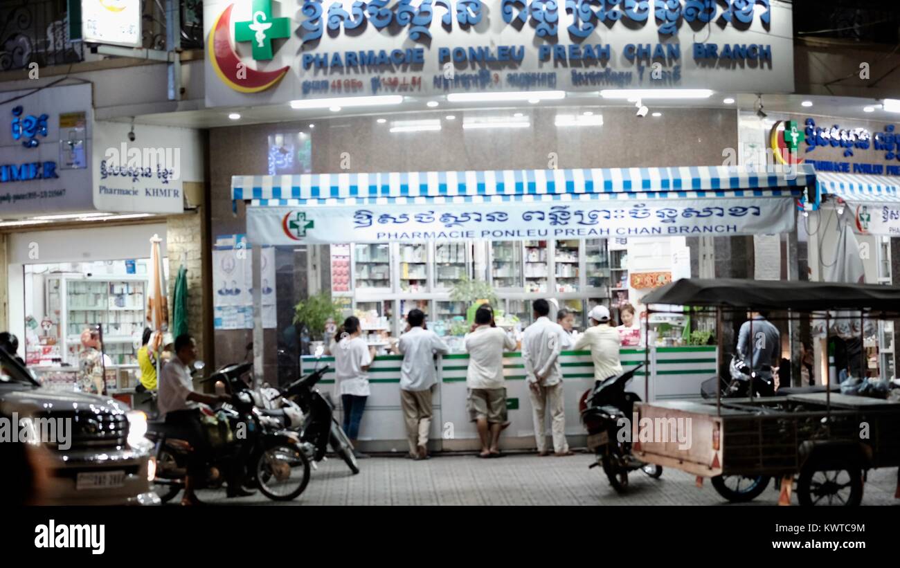 pharmacy drug store chemist pill sellers over-the-counter drugs Phnom Penh Cambodia costumers at counter at night prescription medicine business Stock Photo