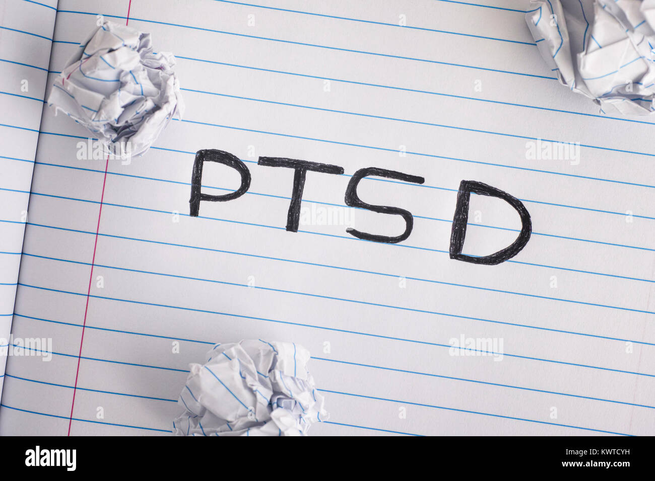 Post Traumatic Stress Disorder. Abbreviation PTSD on notebook sheet with some crumpled paper balls on it. Close up. Stock Photo