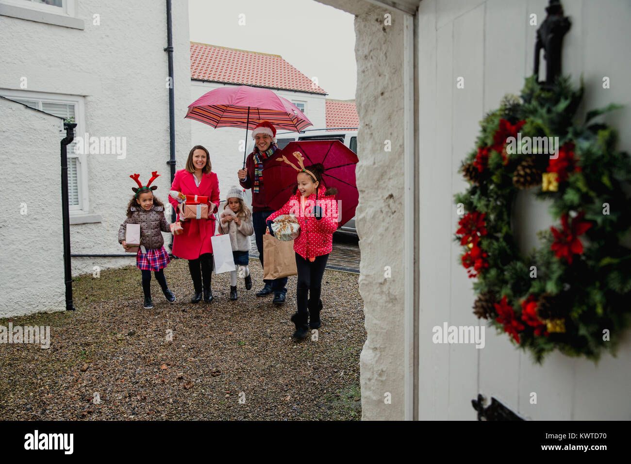 Cheerful family are walking to grandmas house for christmas. They are wearning christmas decorations and carrying presents and gifts. Stock Photo