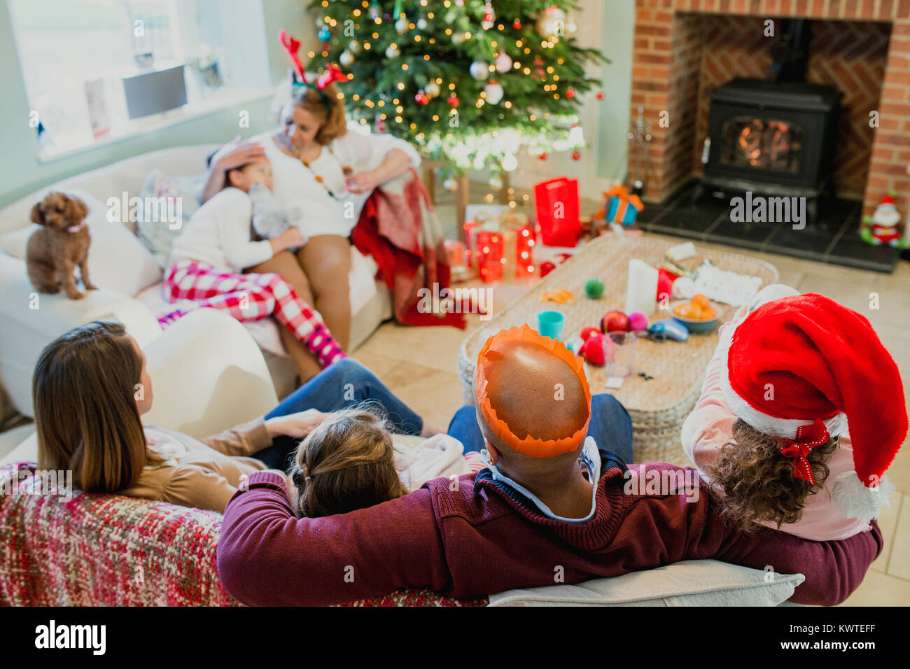 Tired family relacing together in the living room of their home at ...