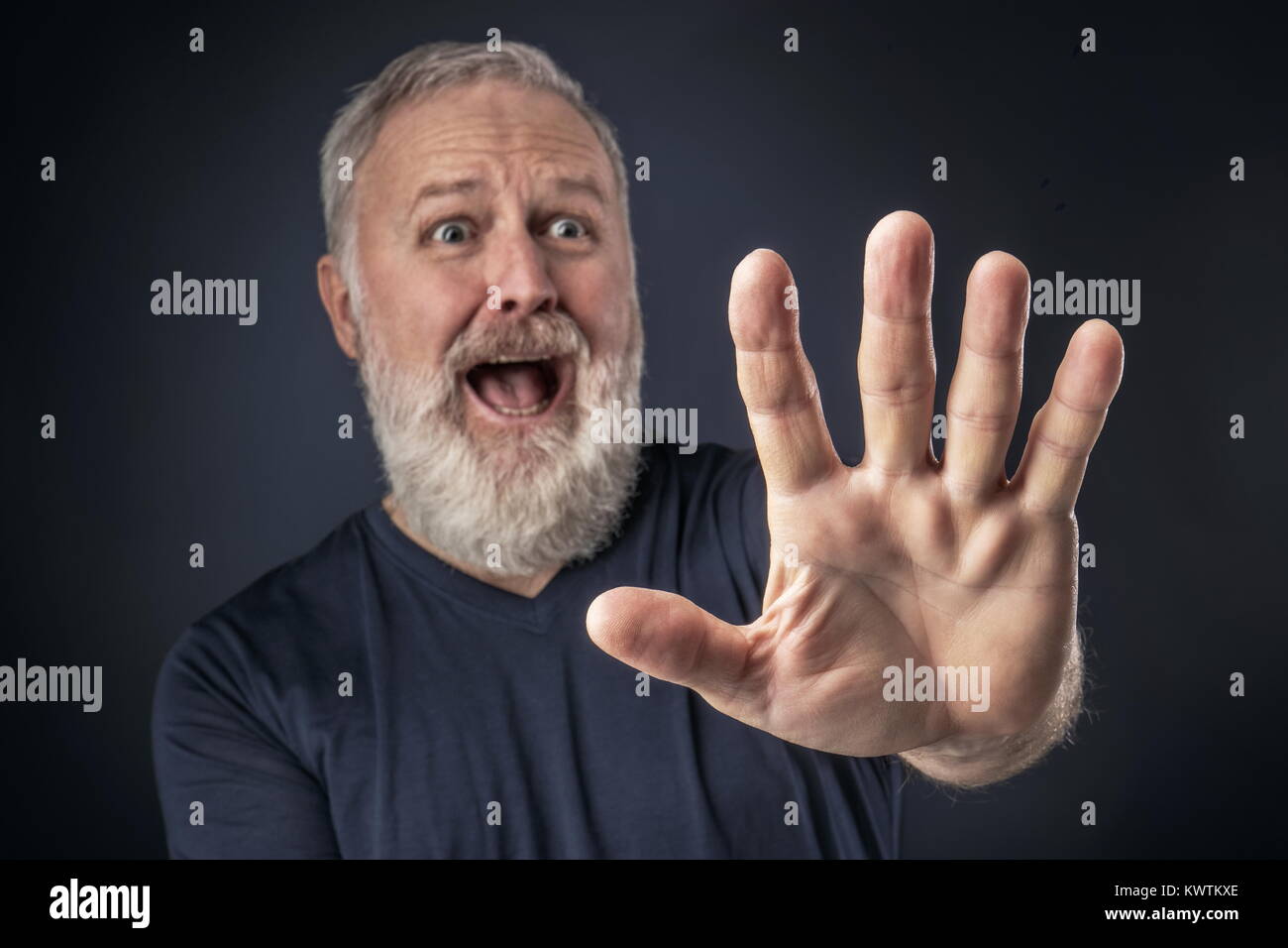 Old man in shirt and scared with his stretched hand forward Stock Photo
