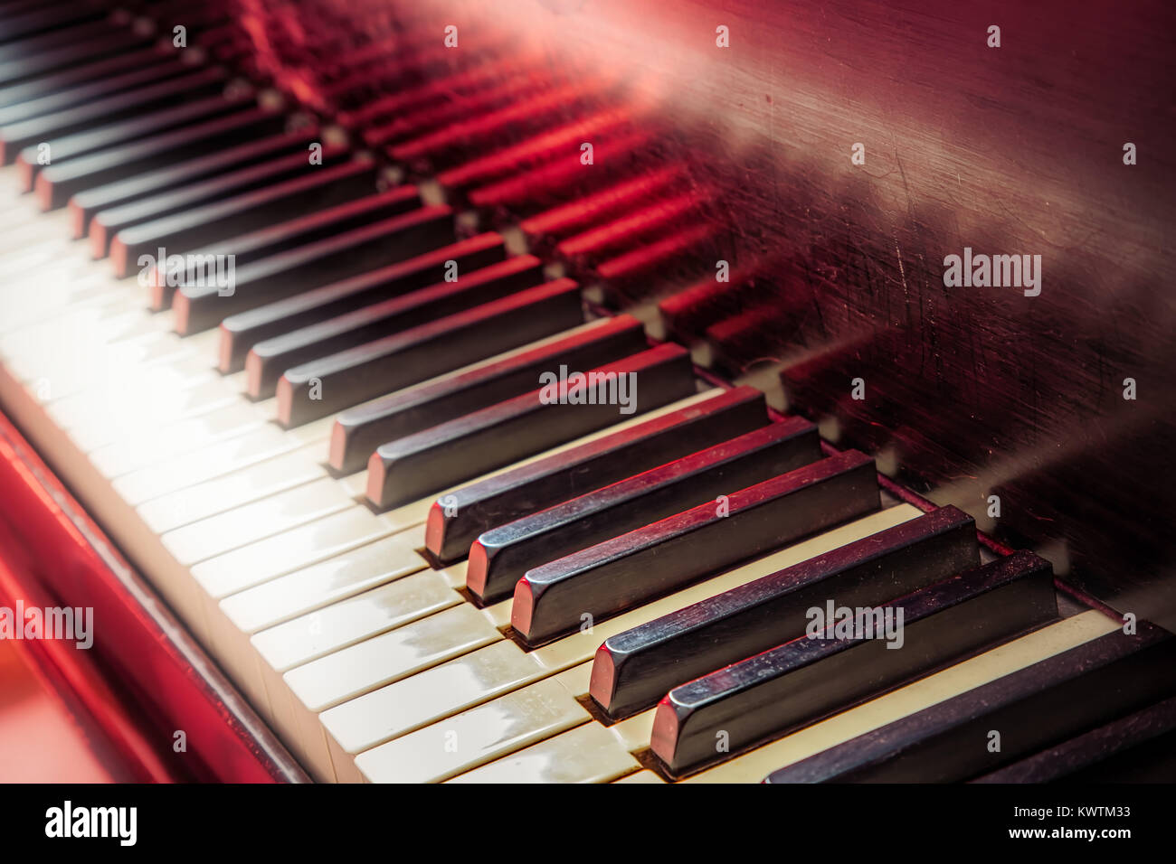 The keys of a piano with a red light in the background. Stock Photo