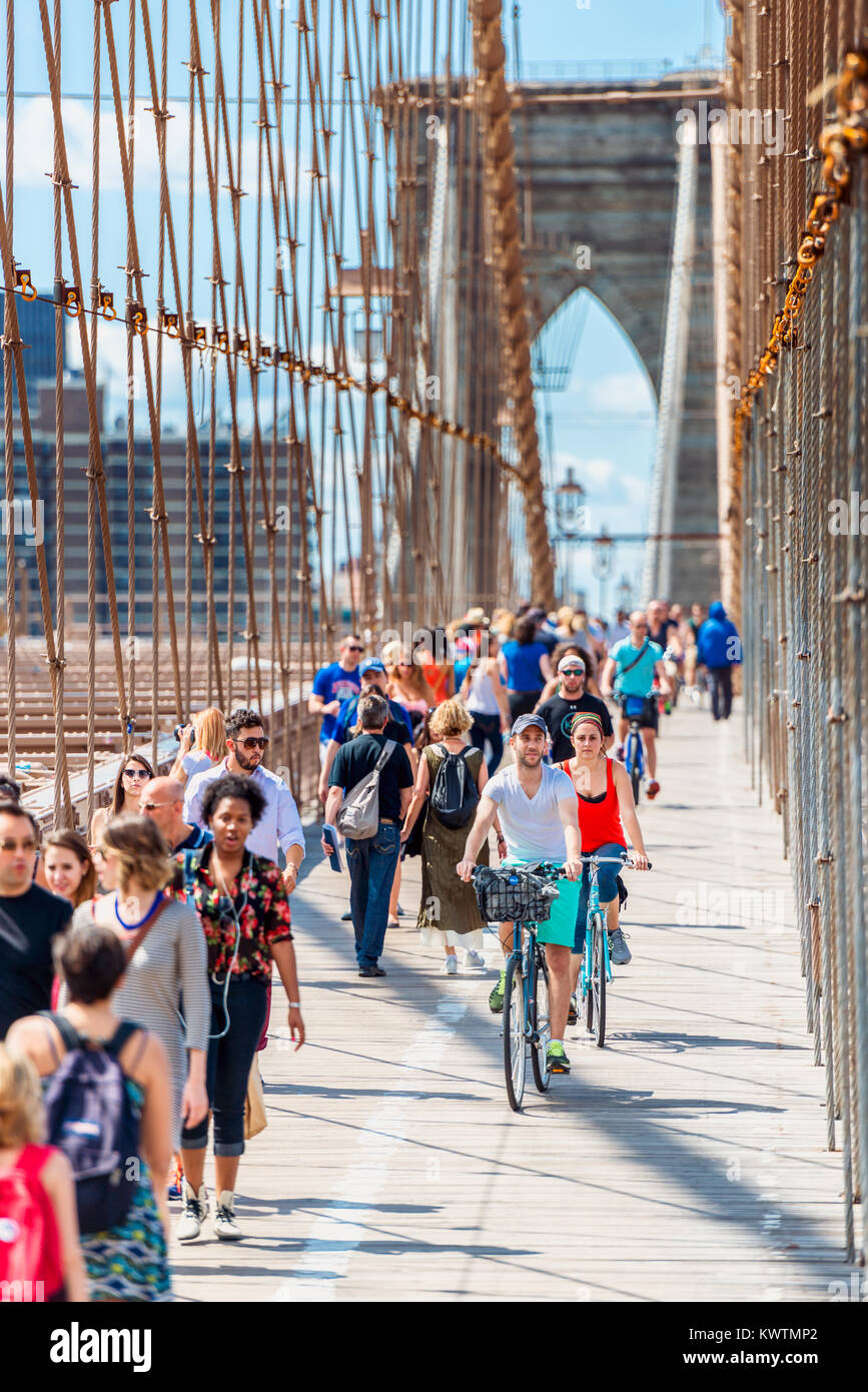 People walking and Cycling on the Brooklyn Bridge in New York City, USA. The Brooklyn Bridge is a very popular tourist attraction. Stock Photo