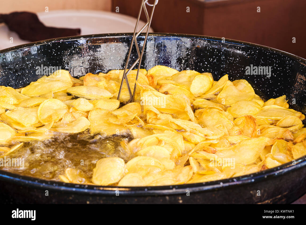 frying chips in a black pan with a lot of boiling oil in a restaurant
