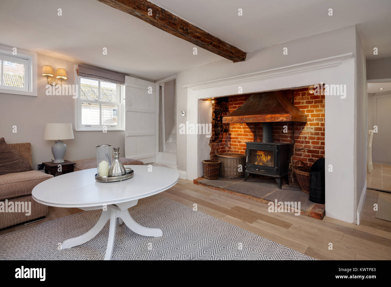 Beautiful Cottage living room with traditional redbrick fireplace containing a cast iron stove and simple surround decorated in shades of white Stock Photo