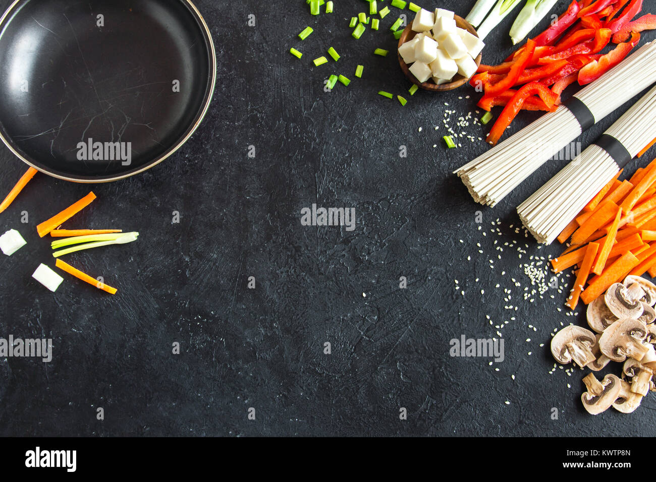 Vegetarian cooking ingredients for stir fry with tofu, noodles and vegetables. Asian vegan cuisine ingredients over black stone background with copy s Stock Photo