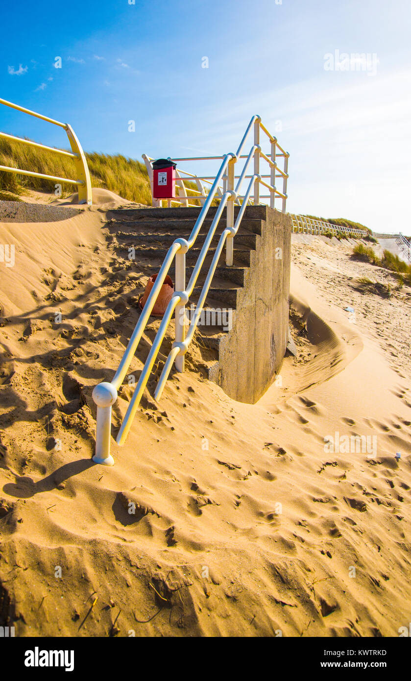 Wind-driven sand piled up against the beach access steps of a sea wall at Aberavon Beach, South Wales, UK. Stock Photo