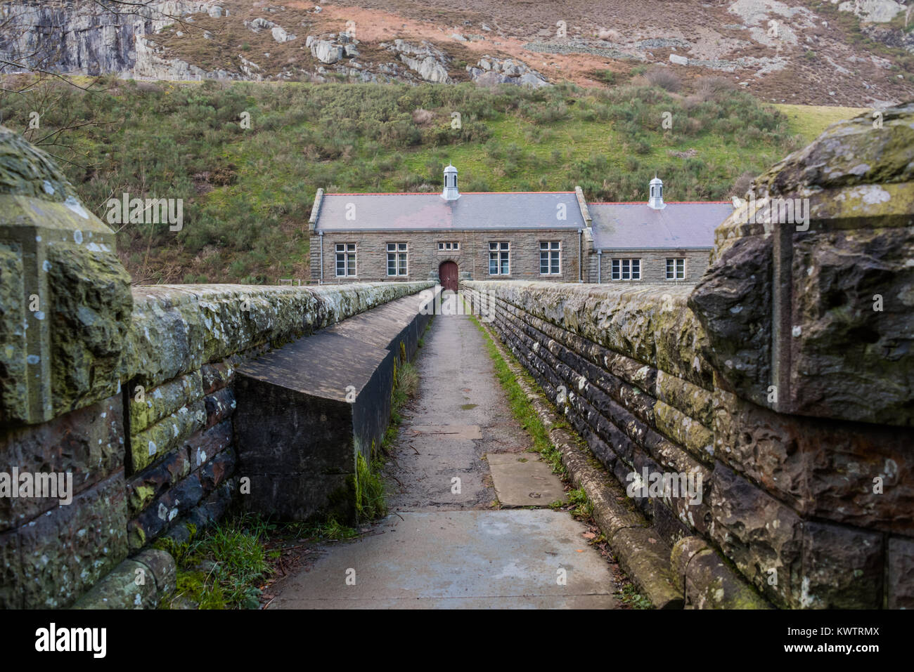 A footpath over a stone bridge leading to a pumping station set in the welsh hills Stock Photo