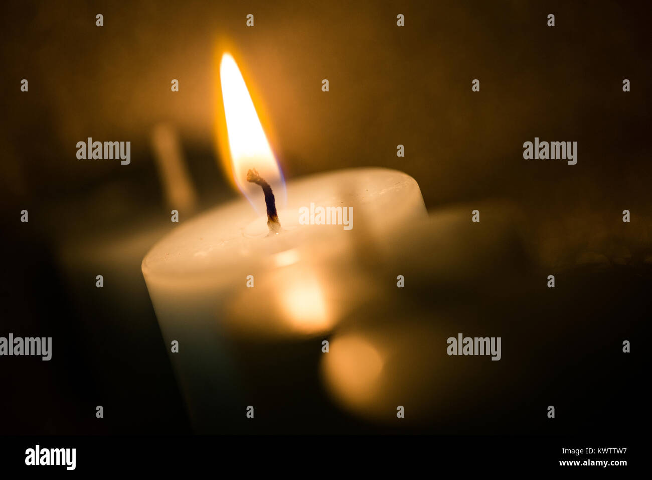 Burning candle with orange tint Stock Photo