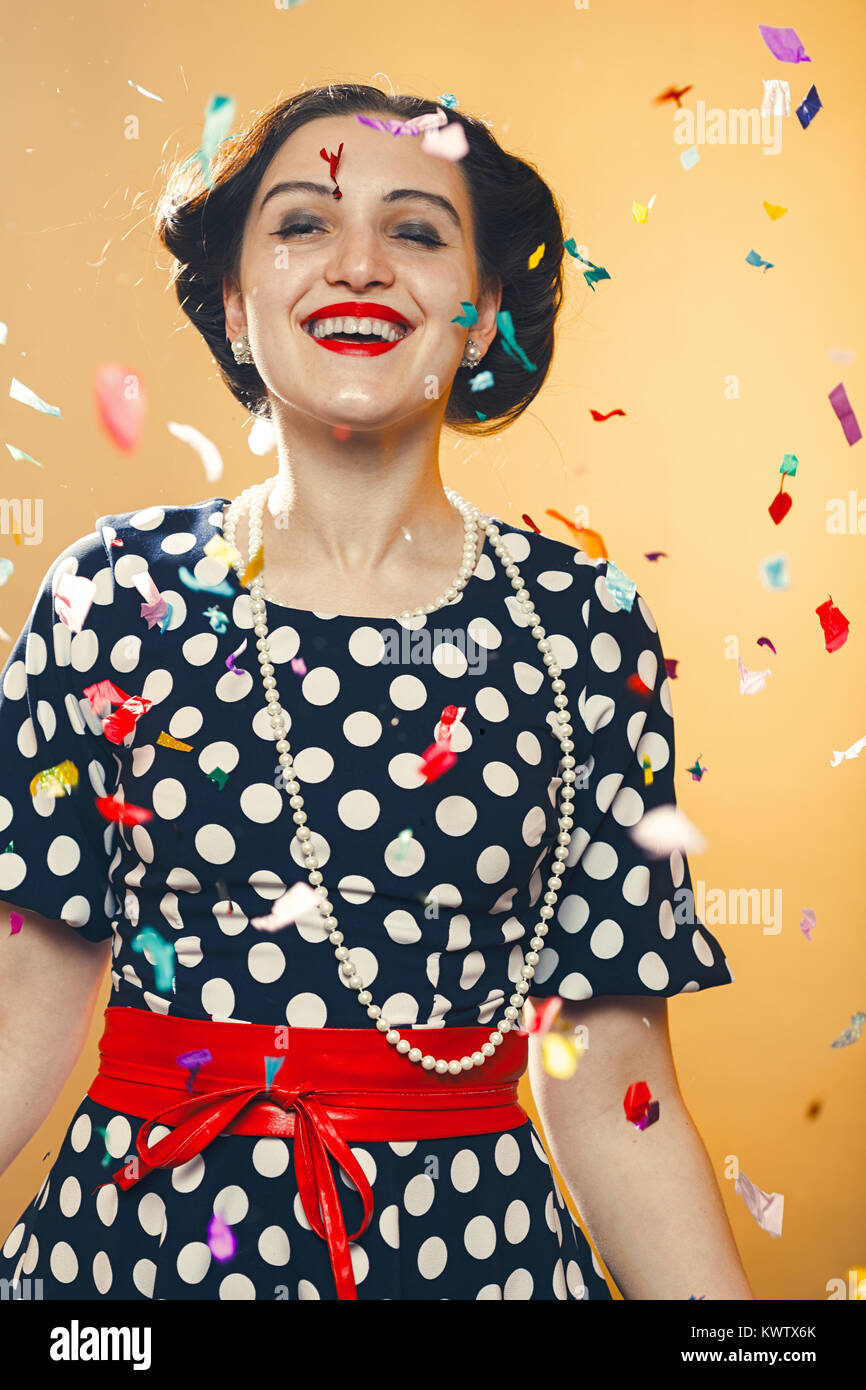 Happy girl on yellow background, colorful confetti slowly scatter and ...
