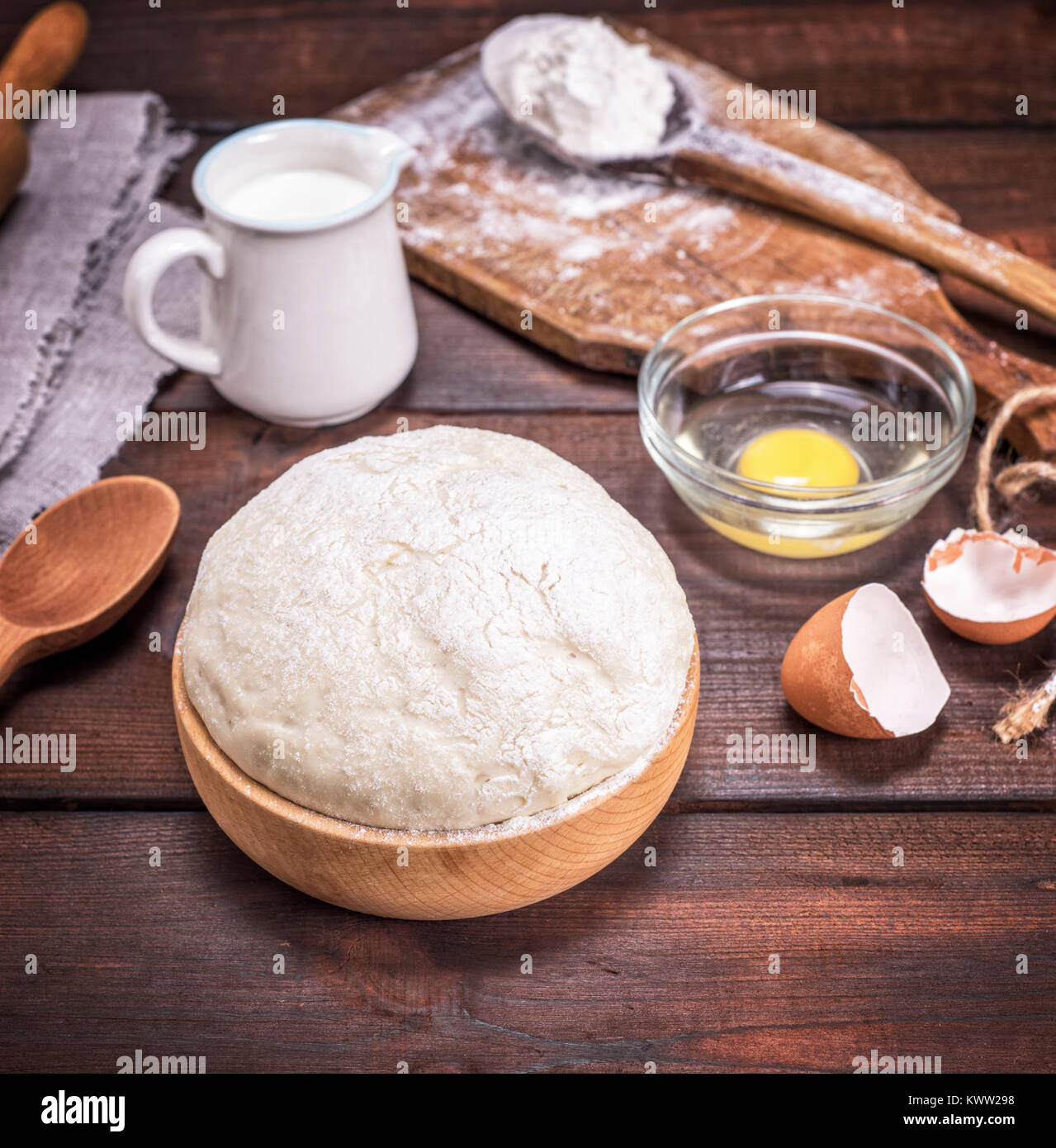 yeast dough in a wooden bowl on a brown table, behind ingredients Stock ...