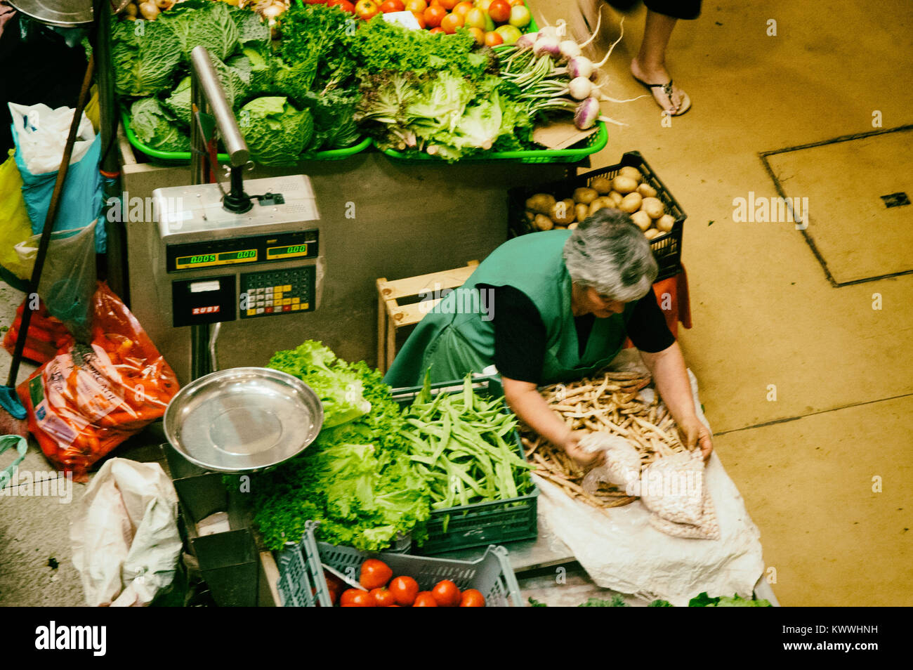 Senior woman sells typical vegetable products at the market bench. Florence, Mercato di San Lorenzo. Italy Stock Photo