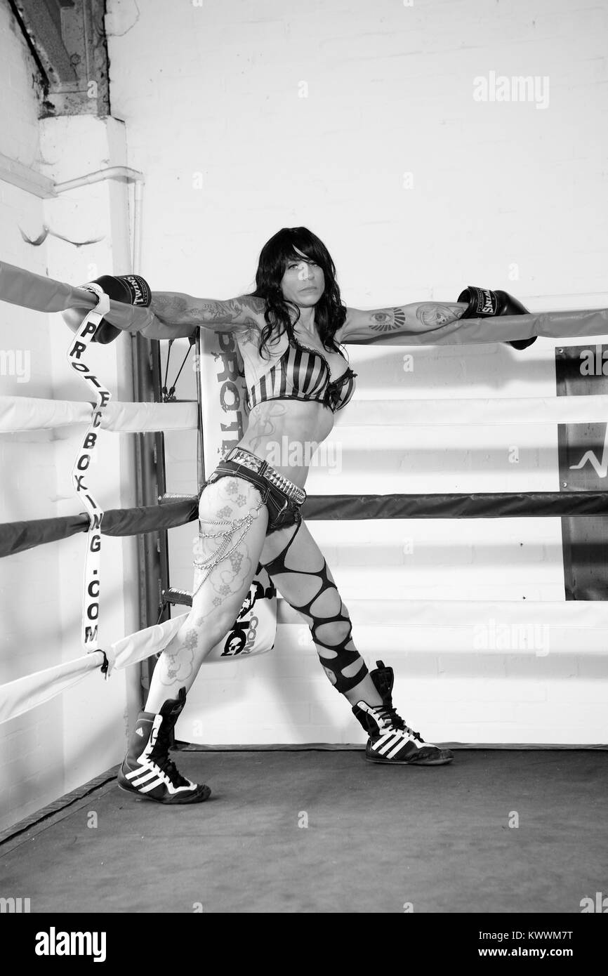 Girl with tattoos in a boxing ring wearing boxing gloves Stock Photo