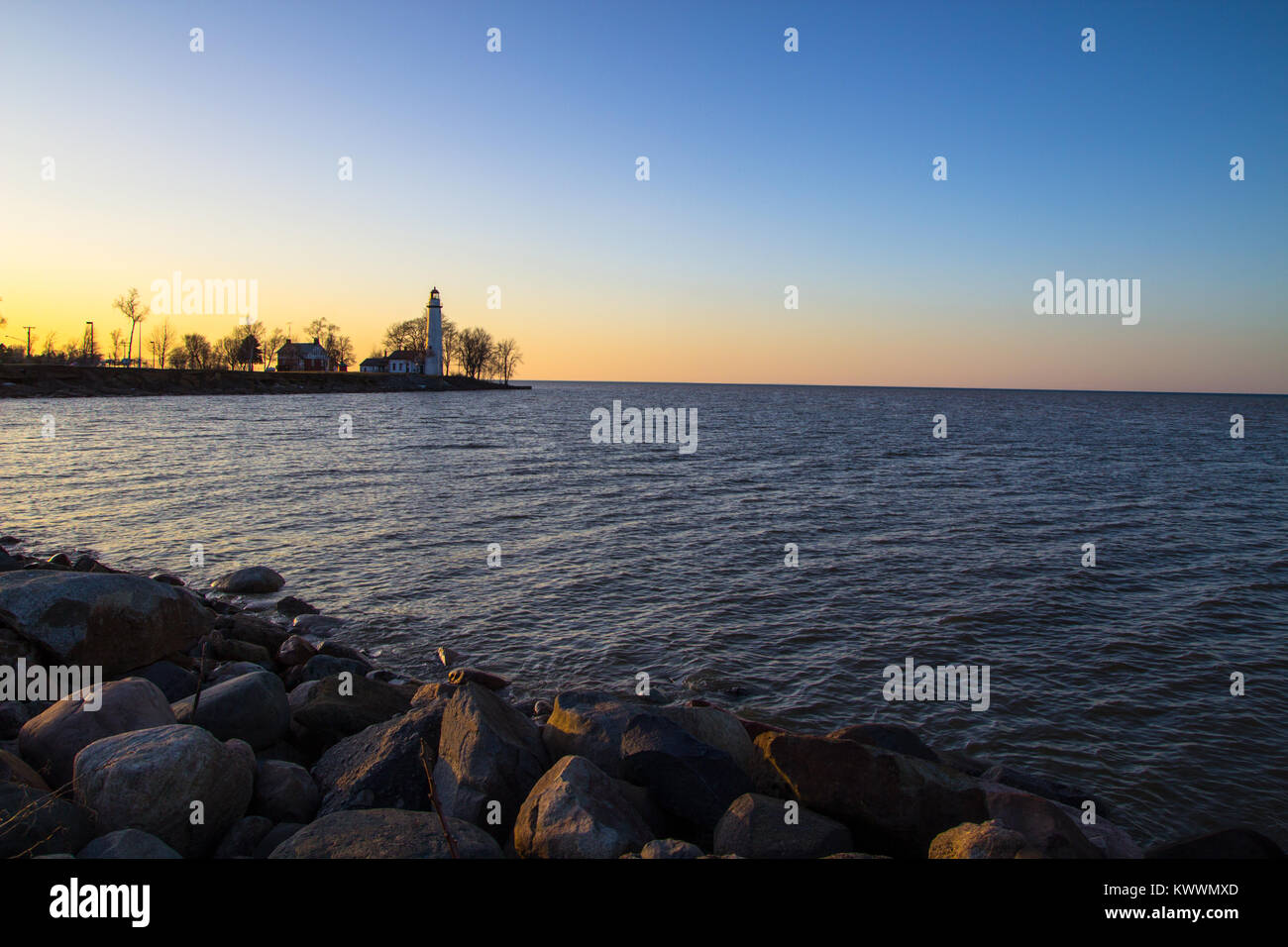 Distant Lighthouse Shore. Lighthouse on the distant shore of Lake Huron at sunrise. Point Aux Barques Lighthouse, Port Hope, Michigan, USA. Stock Photo