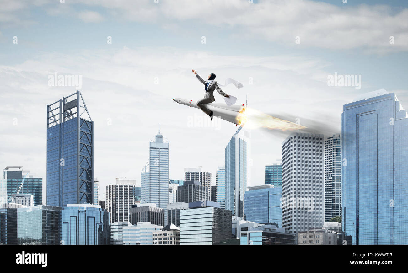 Conceptual image of young businessman in suit flying on rocket with ...