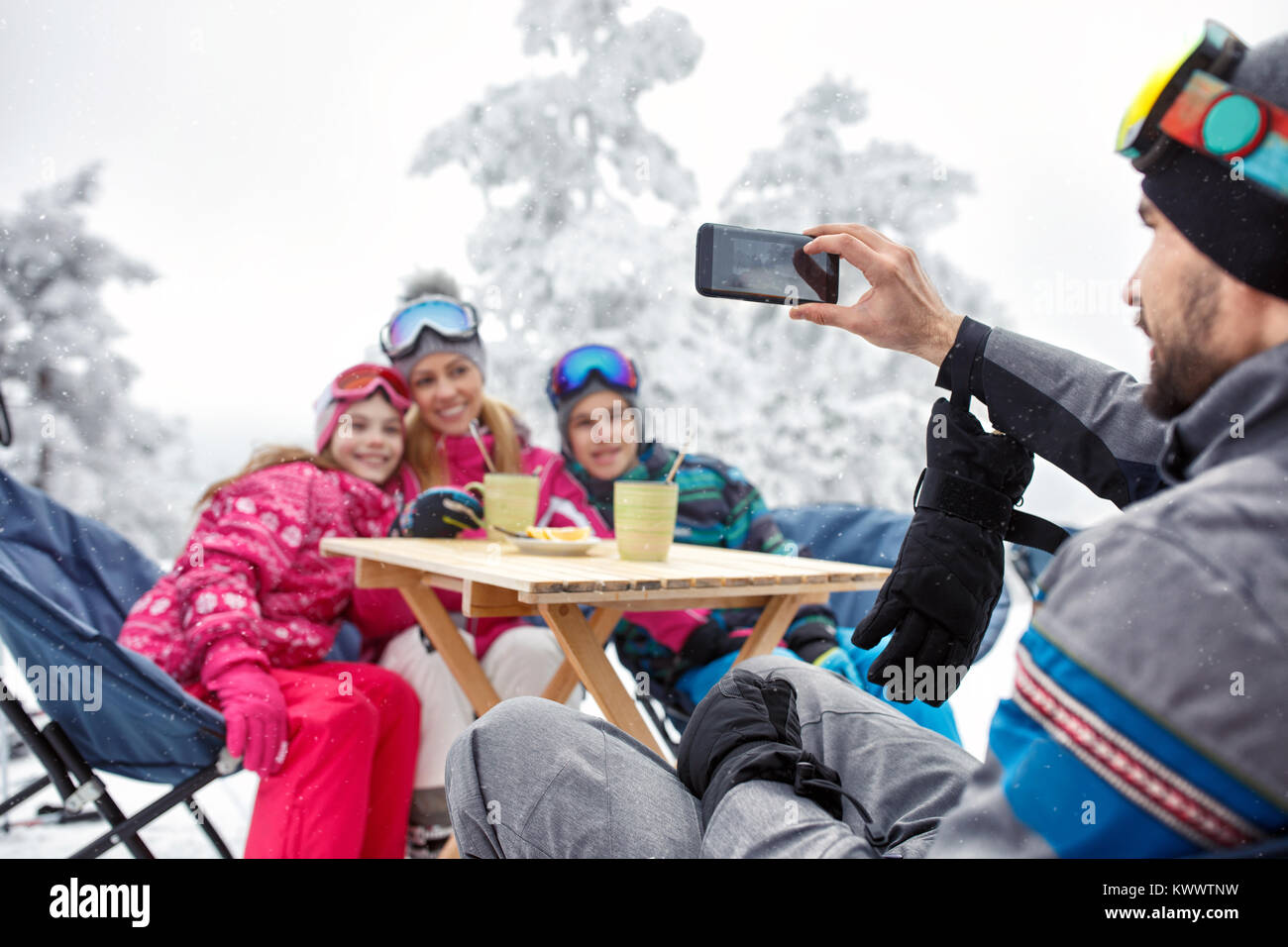 Family at winter holiday in cafe on ski terrain making photos Stock Photo