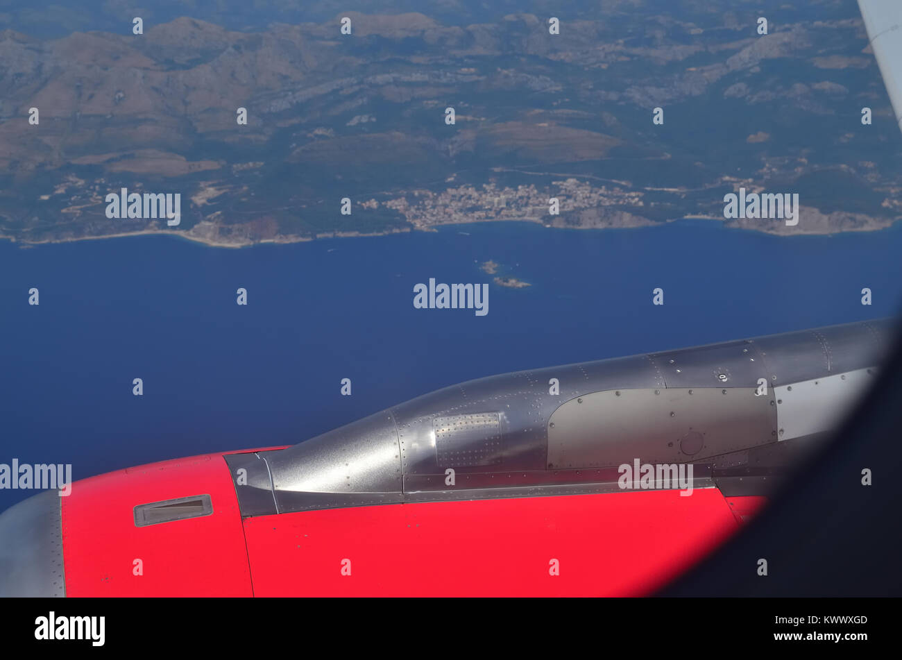 Aerial view from a plane to its red engine, the Adriatic sea, its coastline and a small coastal town Stock Photo