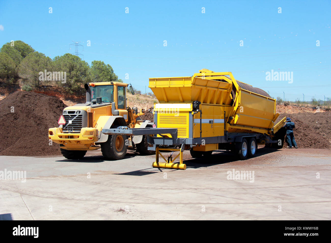 Industrial compost grinder fed by a bulldozer mulching garden waste