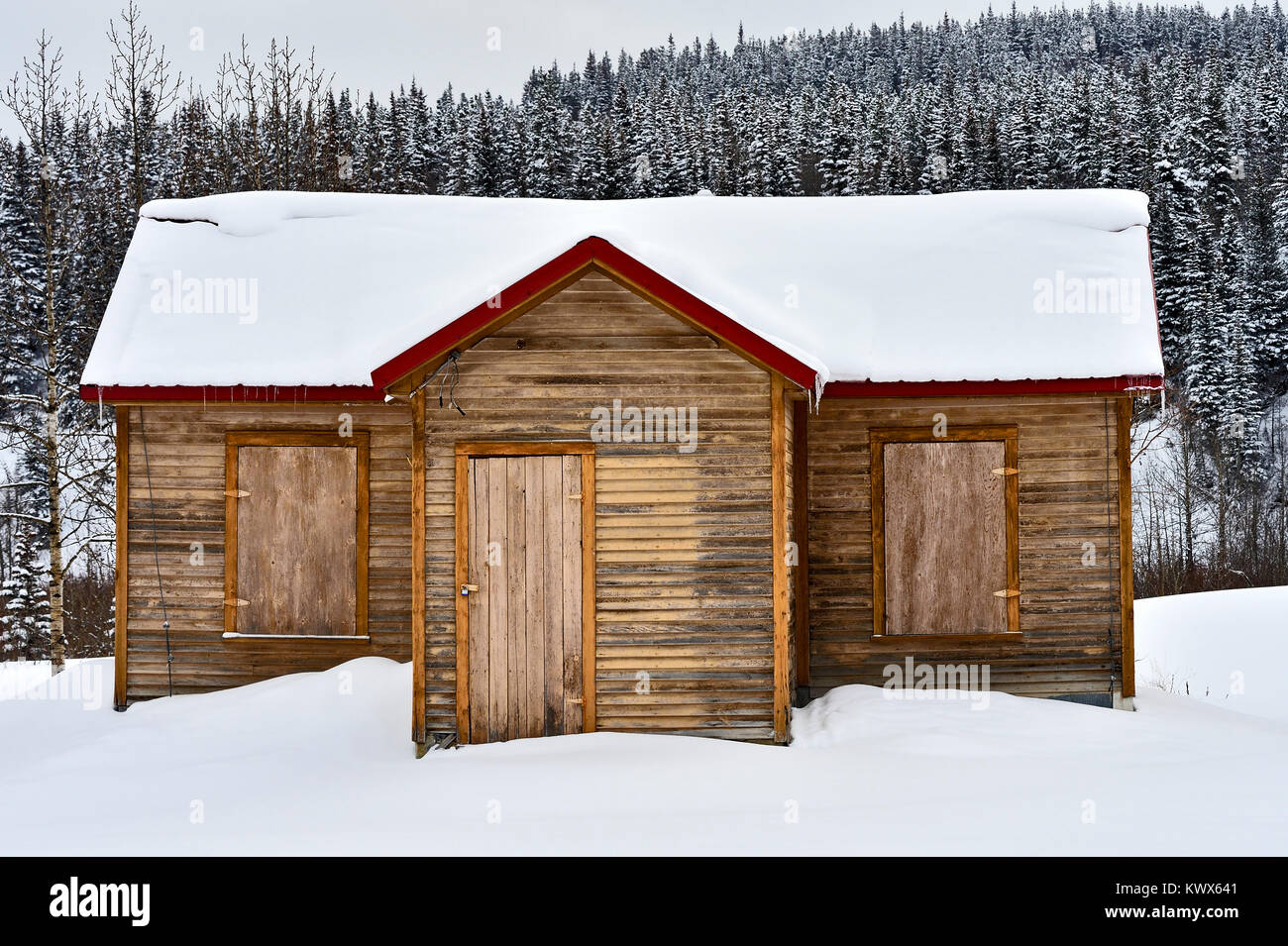 A cabin in rural Alberta that has been closed up for the winter season with wooden window shutters and locked storm door Stock Photo