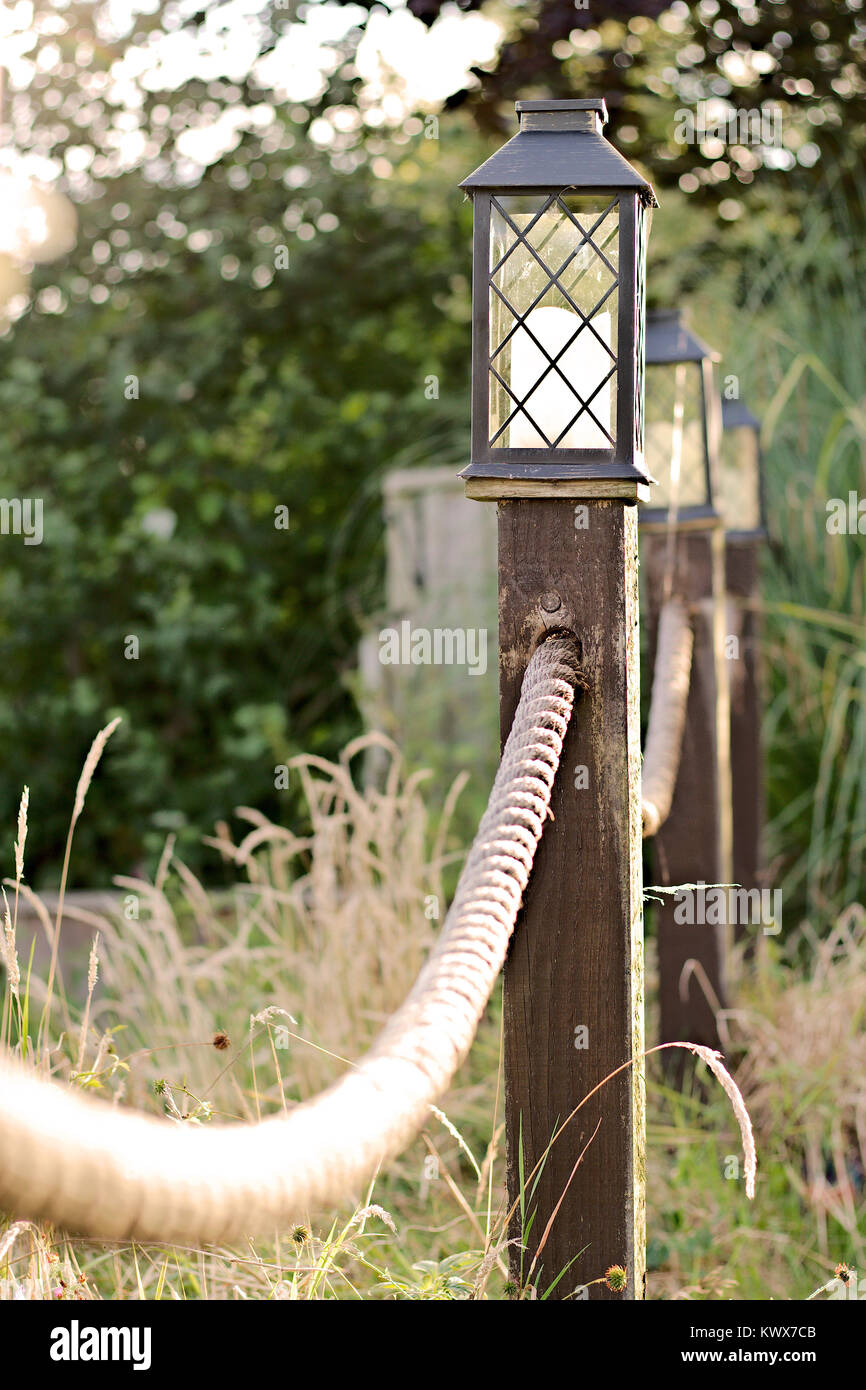 Vintage style solar lights on top of roped posts in a garden setting Stock  Photo - Alamy
