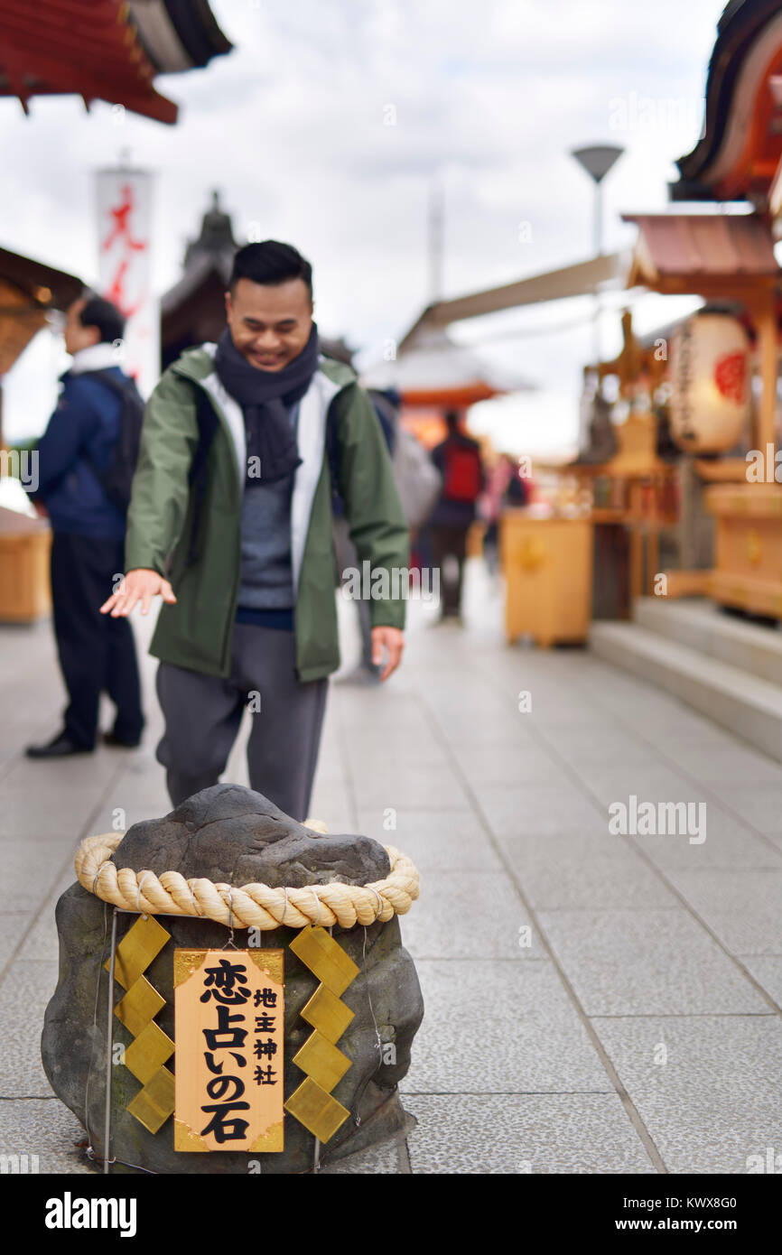 Young man walking with closed eyes towards the love stone at Jishu-Jinja matchmaking shrine to Okuninushi the god of love and marriage, at Kiyomizu-de Stock Photo