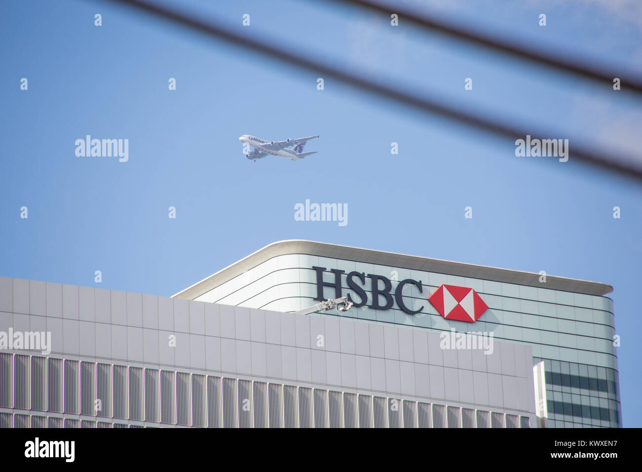 A passenger plane flies over HSBC HQ in Canary Wharf, London Stock Photo