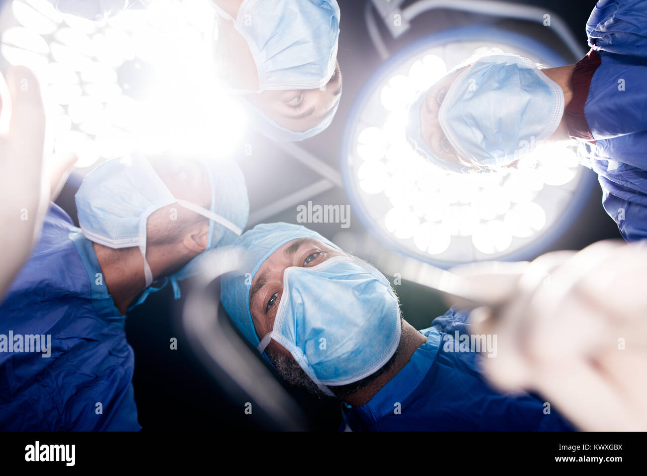 Team of doctors operating under surgery lights in operation theater. Point of view shot of surgeons performing dental surgery in hospital. Stock Photo