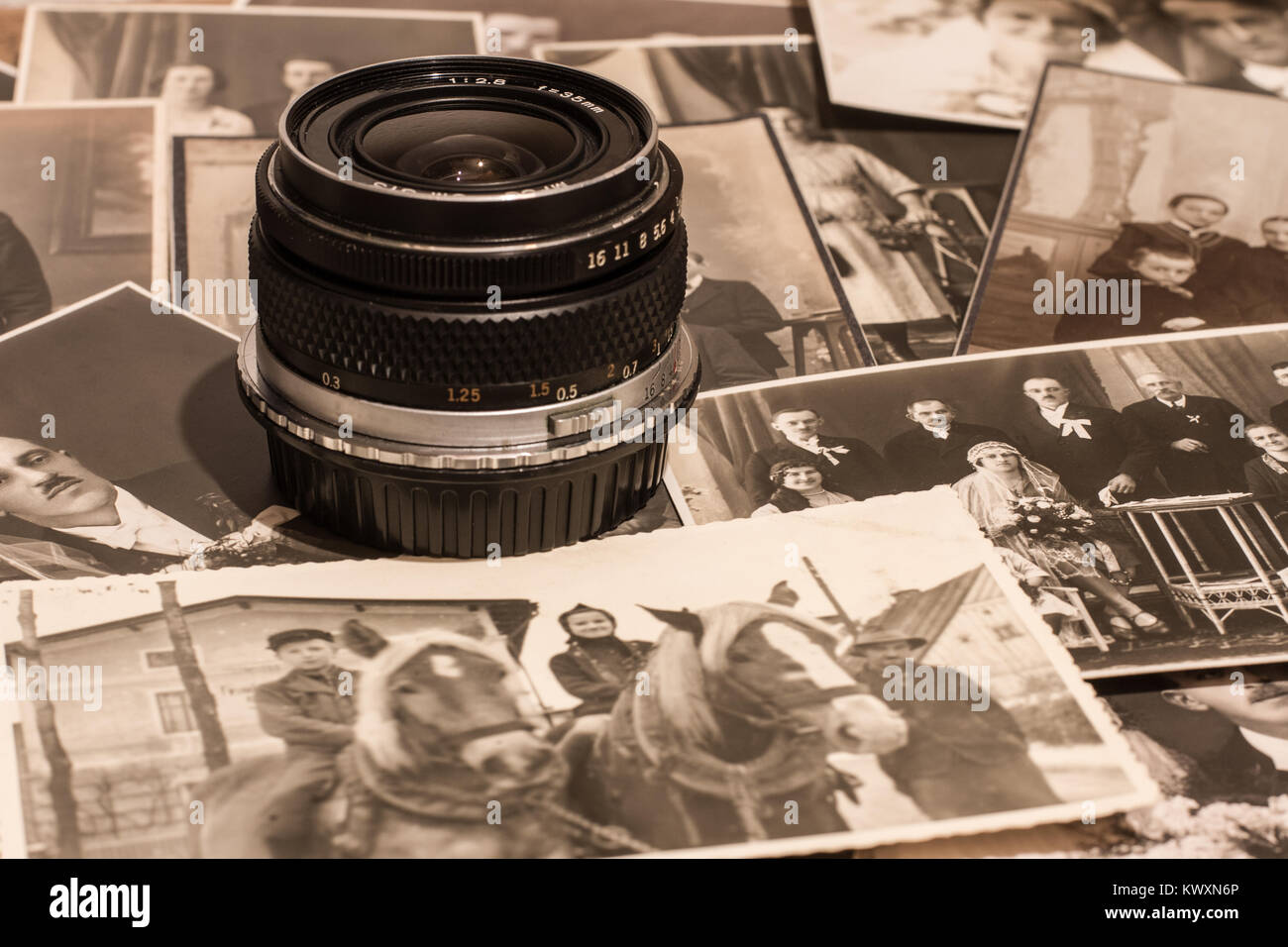 Vintage photographs next to an old camera lens Stock Photo