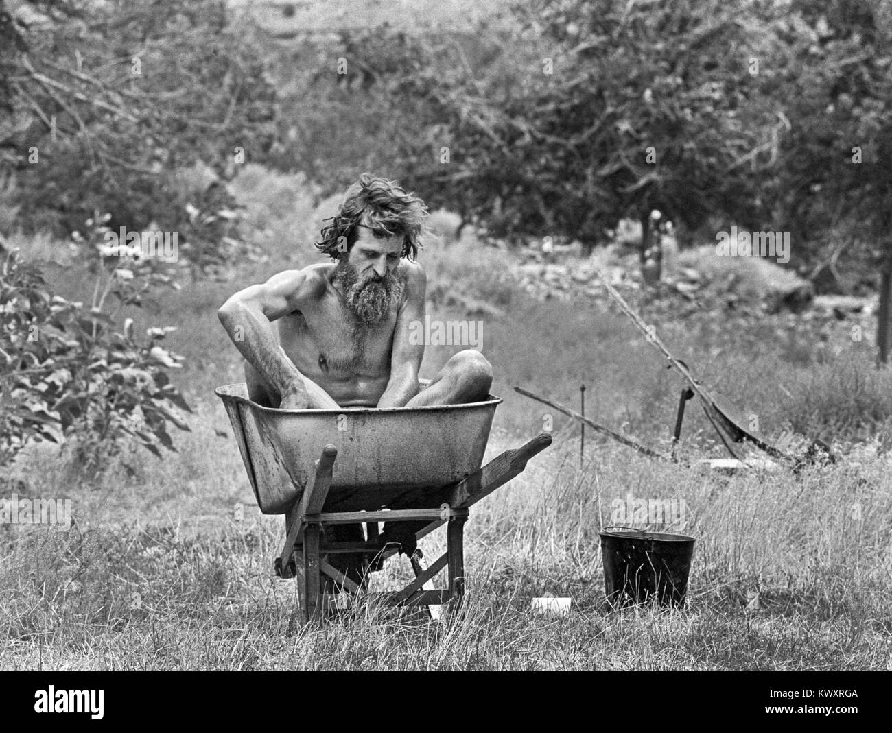 Nik Hougen, an American hermit, bathes in an old wheelbarrow, at his remote residence in Desolation Canyon, Utah, along the Green River. Stock Photo