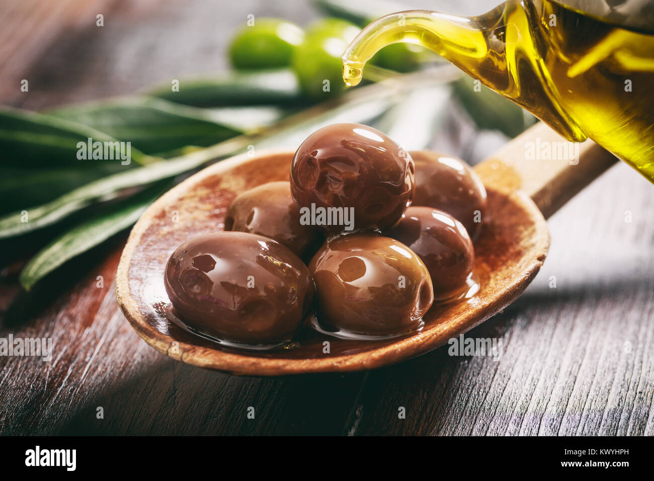 Olives in a wooden spoon and olive oil Stock Photo - Alamy