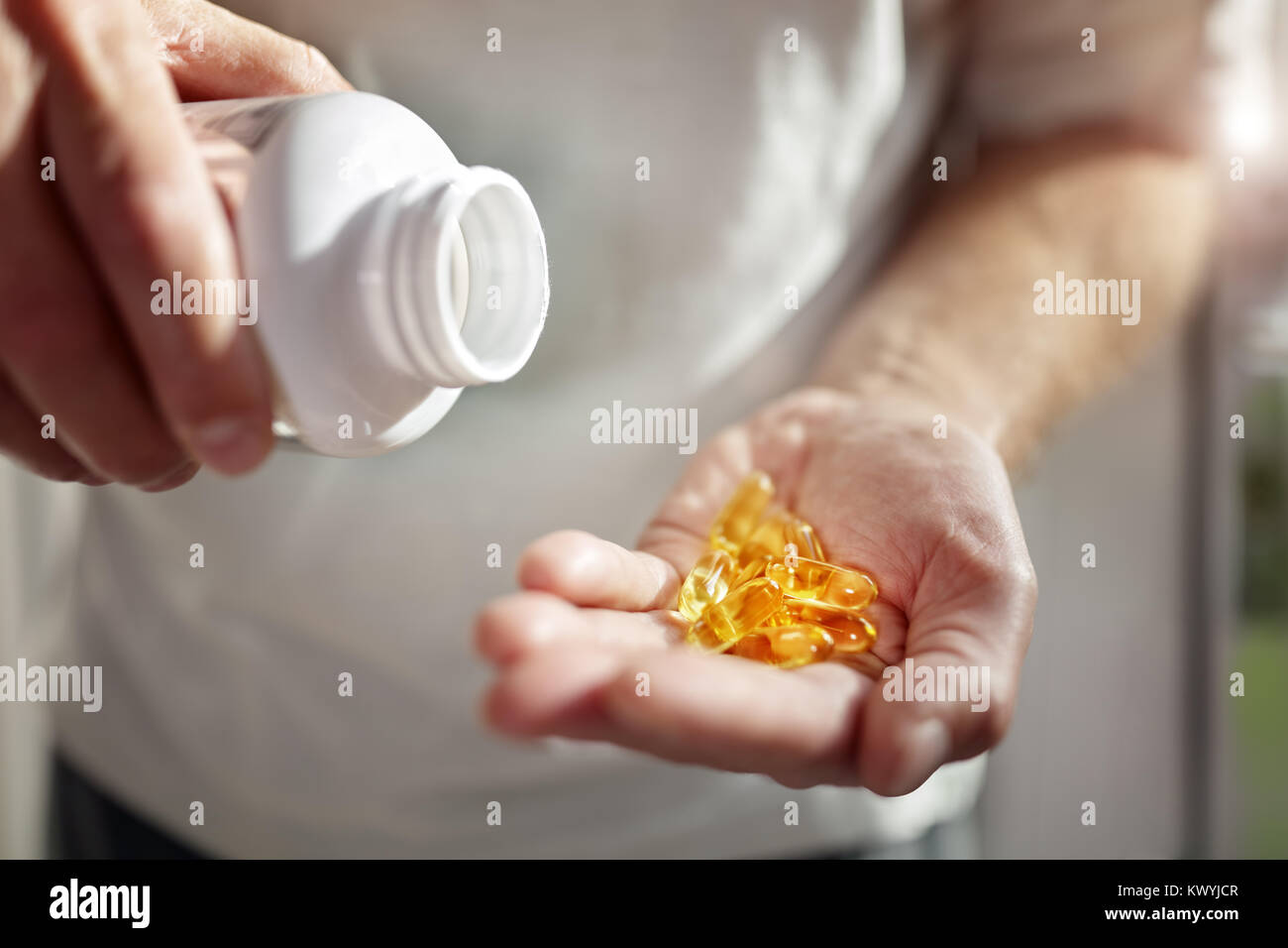 Bottle of omega 3 fish oil capsules pouring into hand Stock Photo