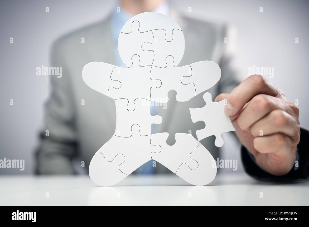 Businessman assembling jigsaw puzzle human team employee concept Stock Photo