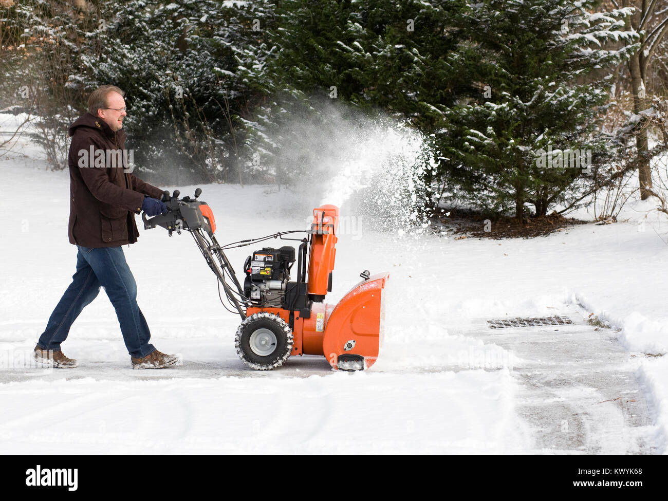 A man clearing the snow using a home snow blower. Stock Photo