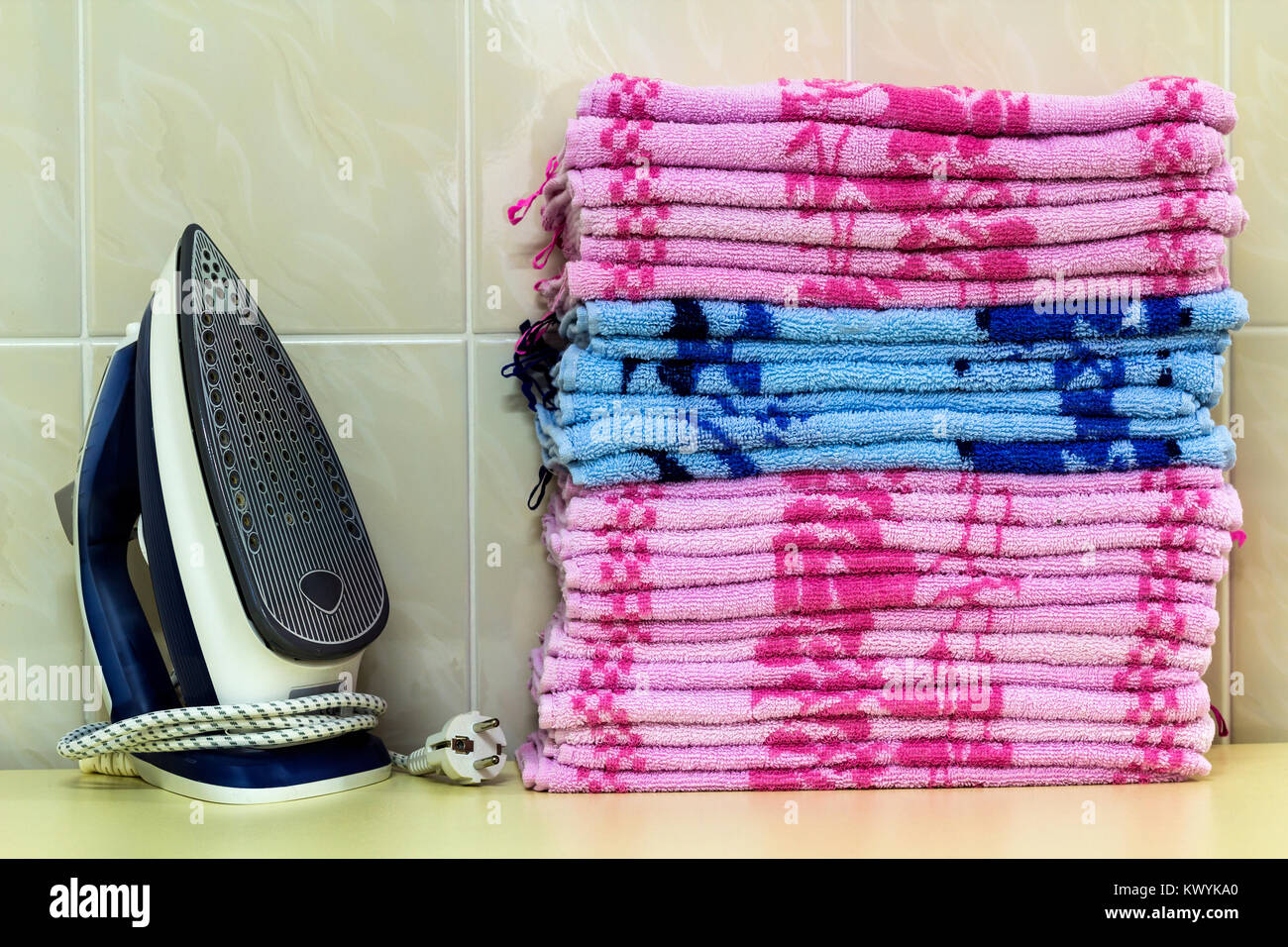 Ironing linen with steam generator. A stack of ironed towels lying next