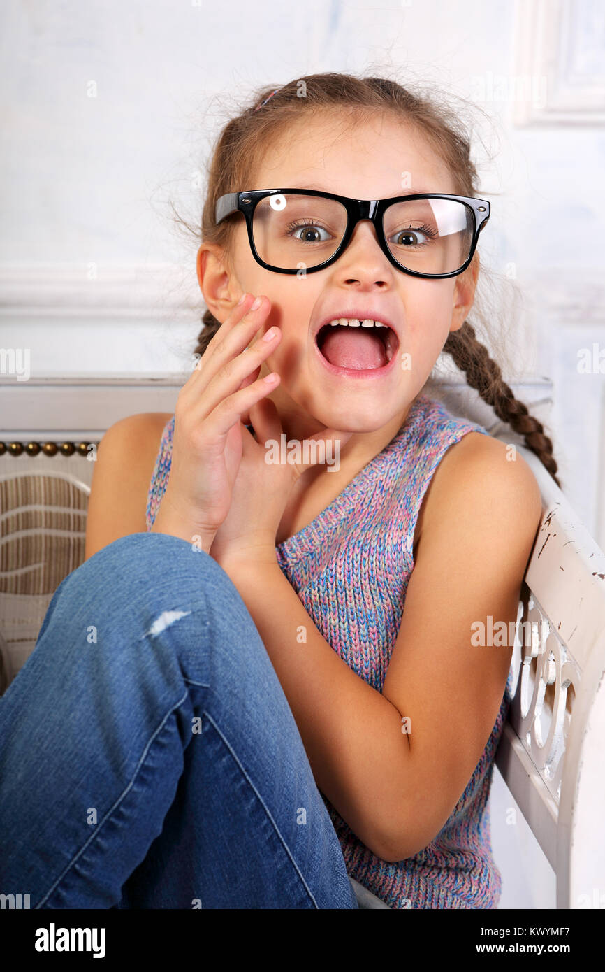 Happy excited surprising kid girl in fashion eyeglasses looking with open mouth. Closeup studio portrait Stock Photo
